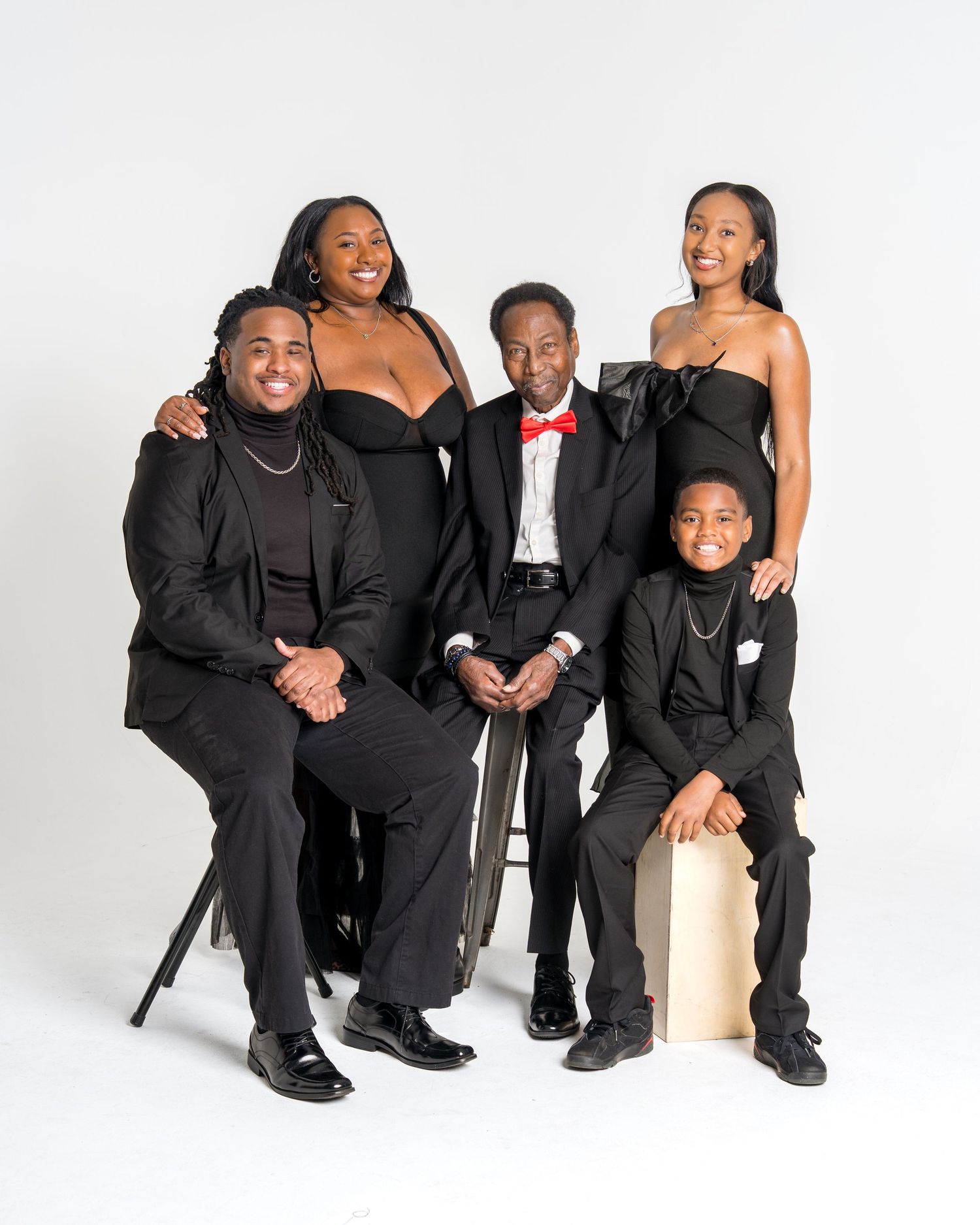 Five family members in formal black attire during a studio portrait session