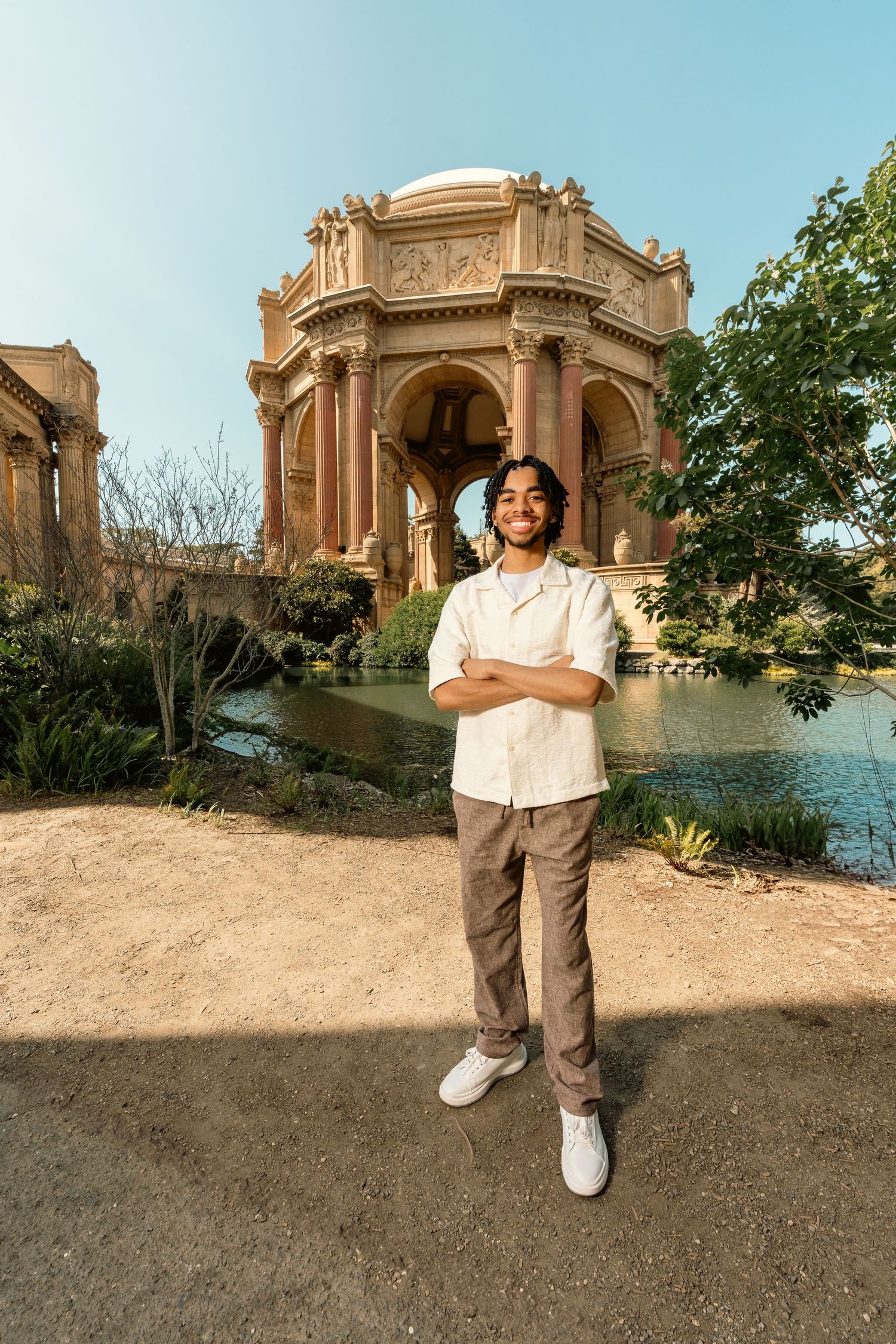 Smiling young man with crossed arms standing before Palace of Fine Arts rotunda in San Francisco.