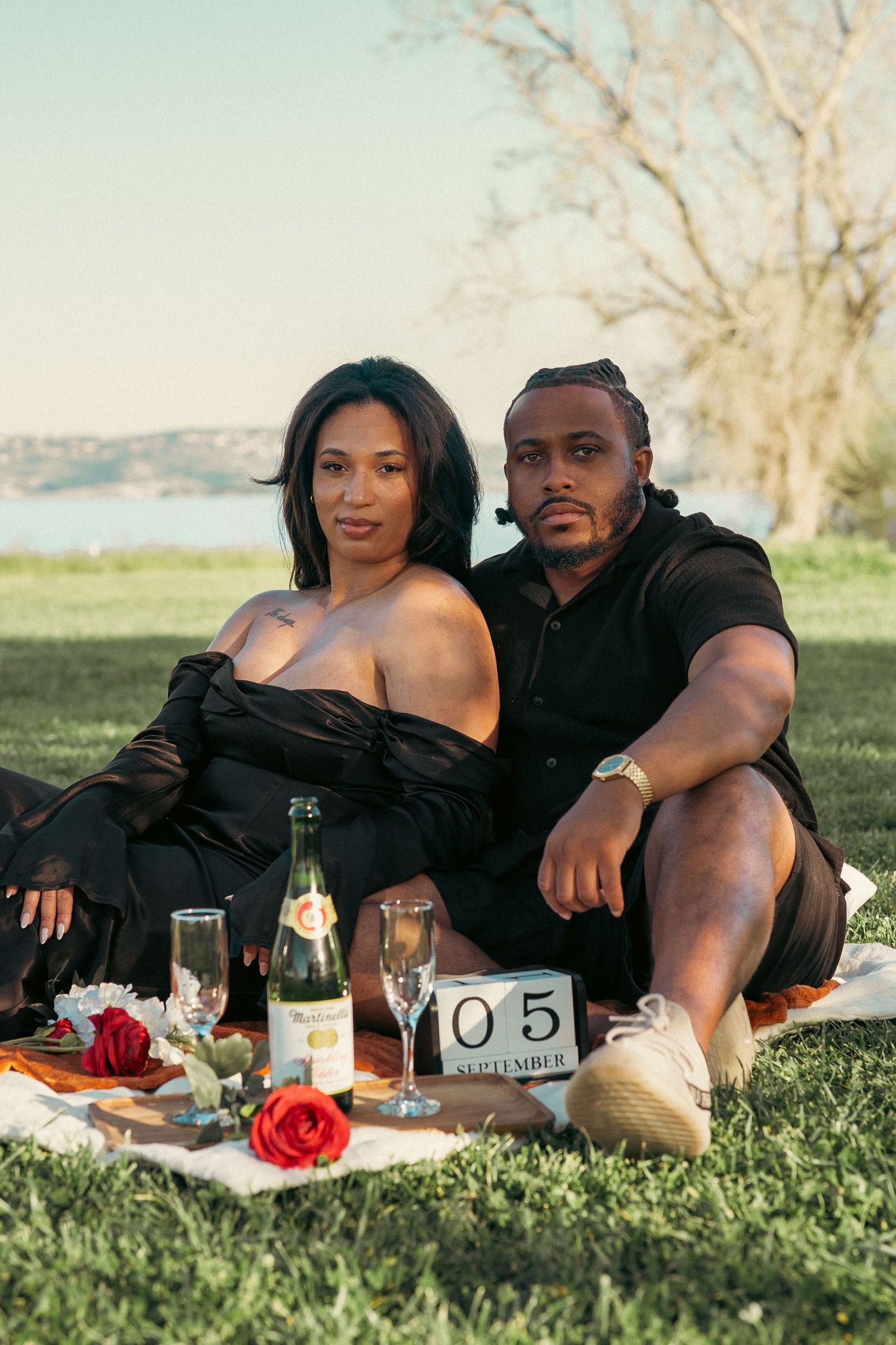 Couple sitting on a picnic blanket with champagne and roses, celebrating their September 5th anniversary.