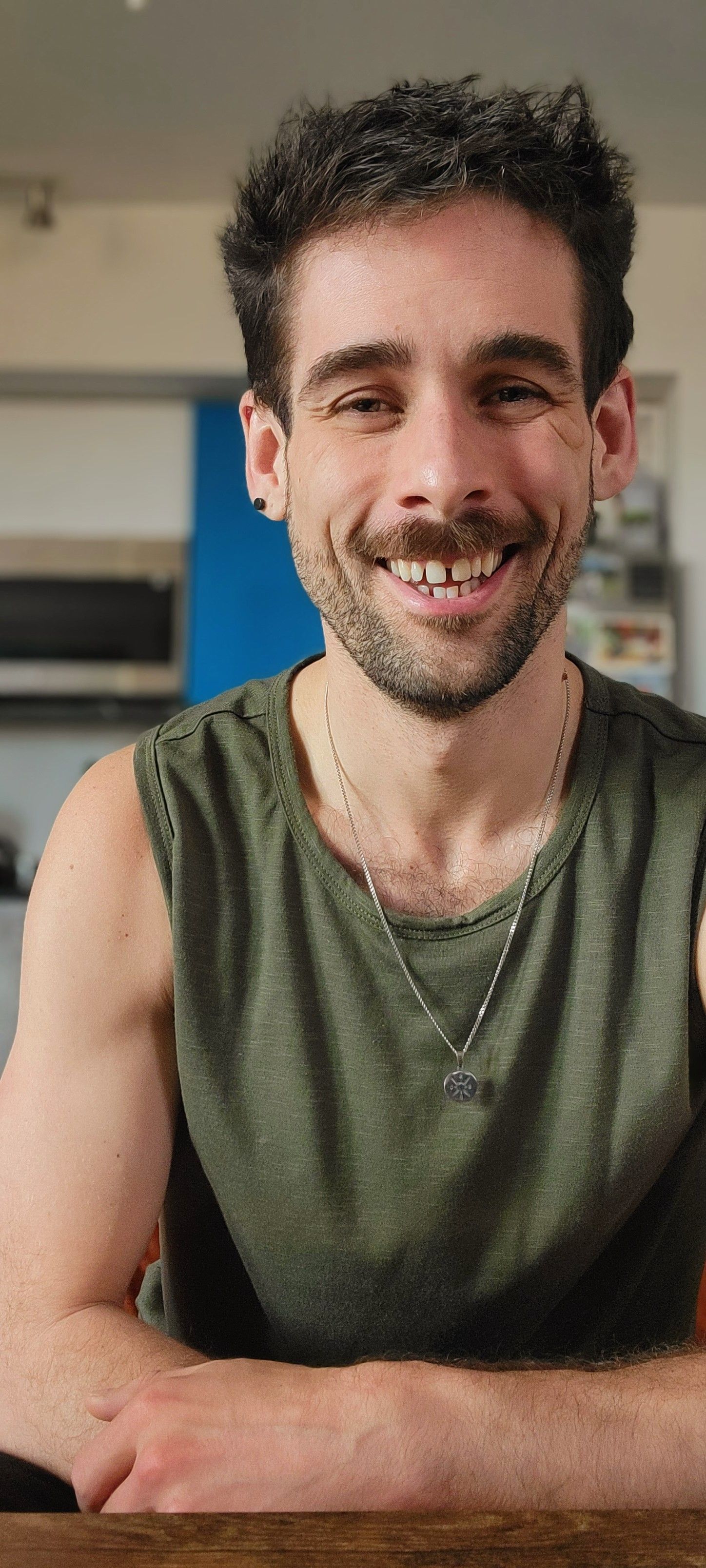 Person in olive green tank top relaxing and smiling at home.