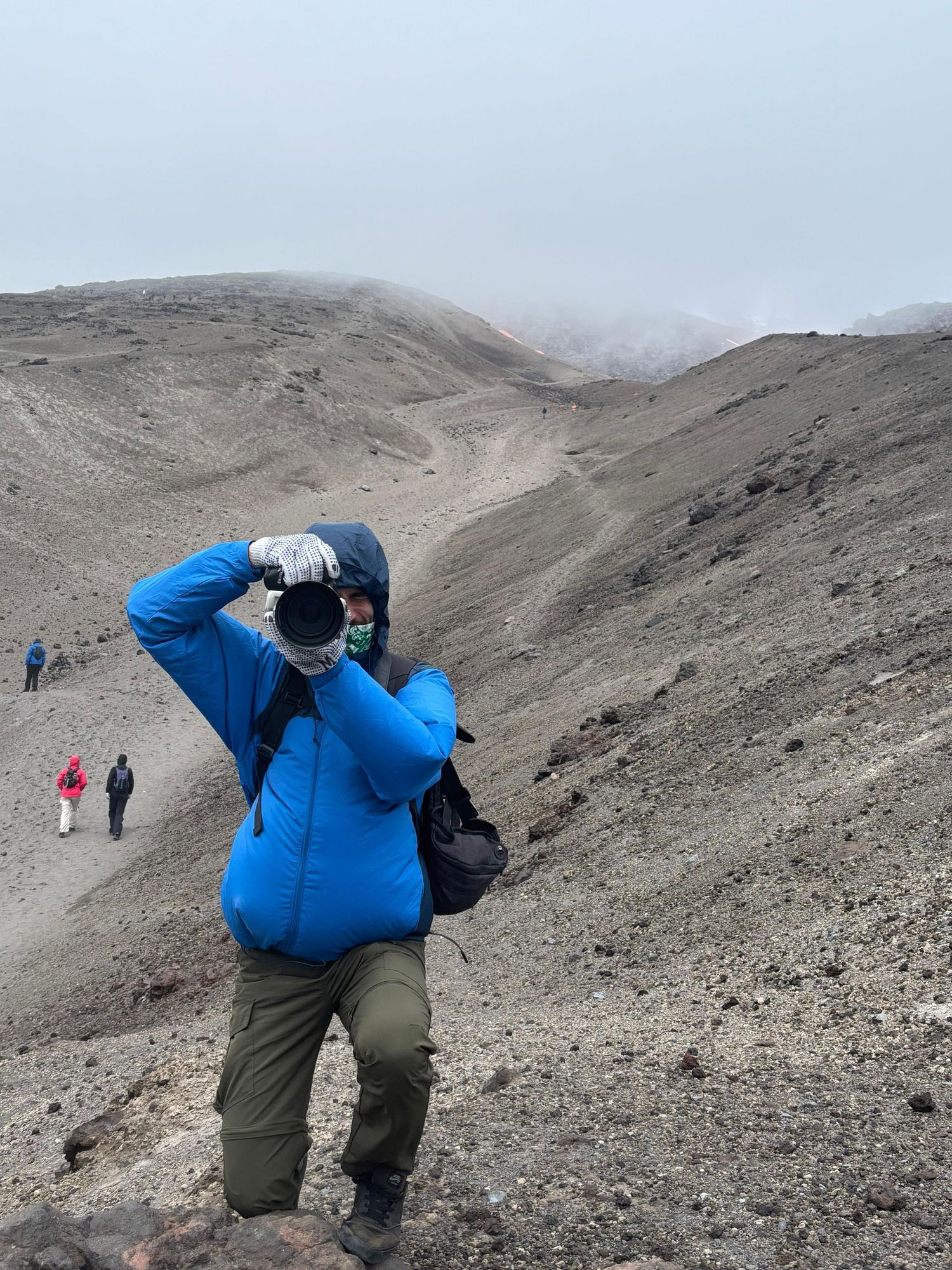 Hikers climbing steep rocky terrain with camera equipment and backpacks.