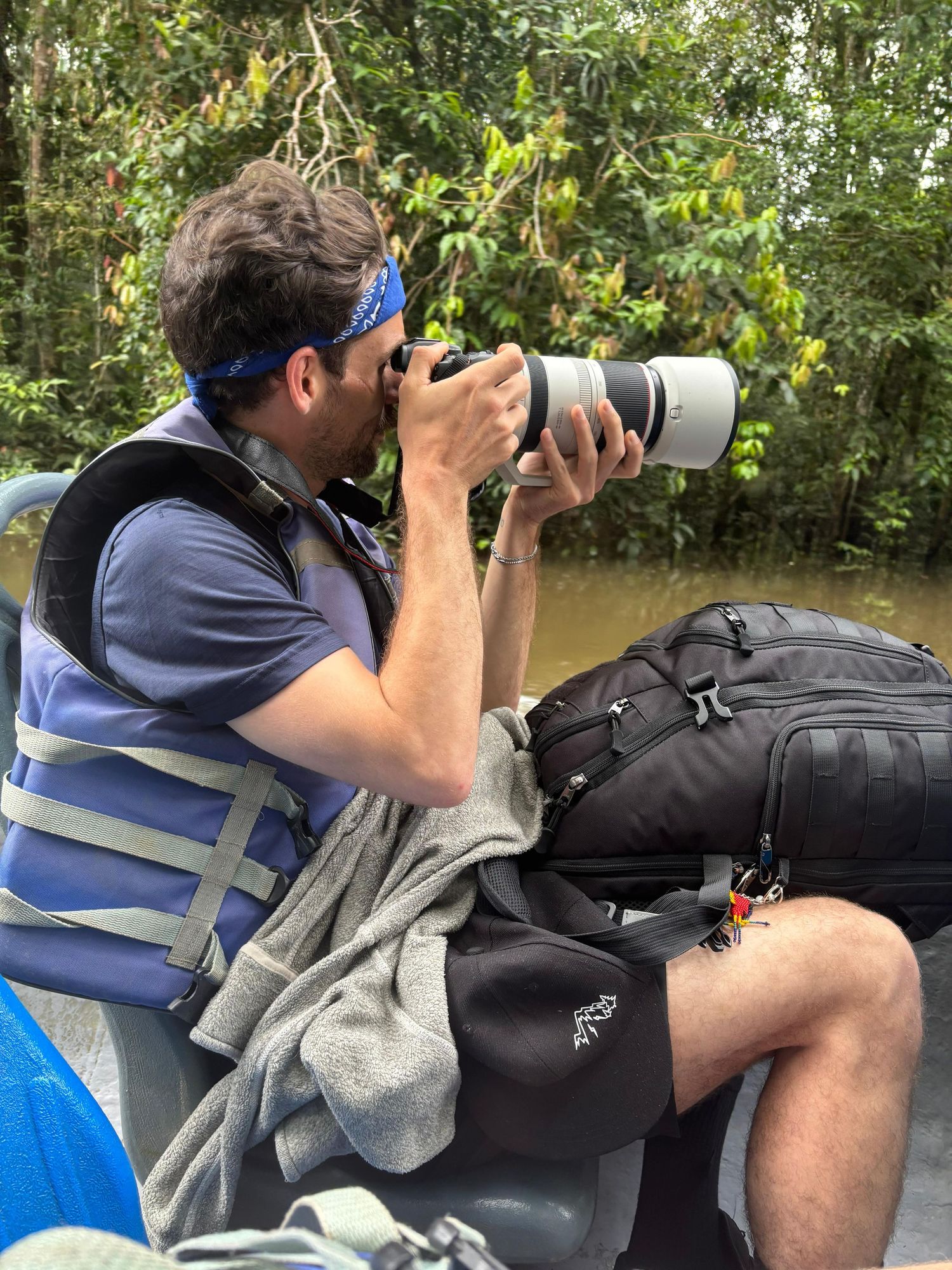 Photographer with camera equipment taking nature shots while sitting on the ground outdoors.