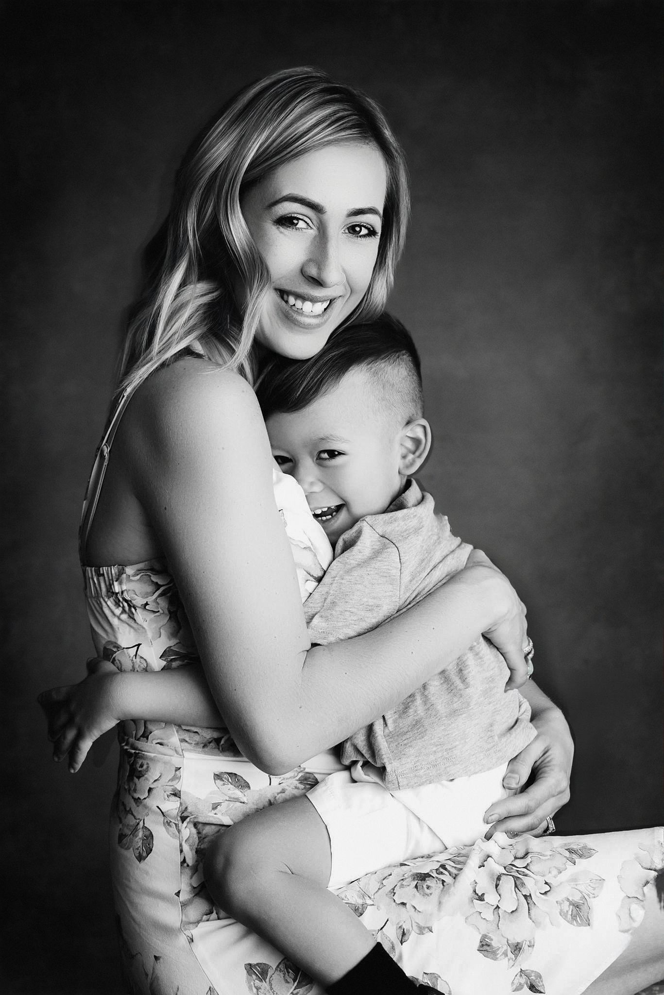 Black and white portrait of a woman holding her son, looking down tenderly