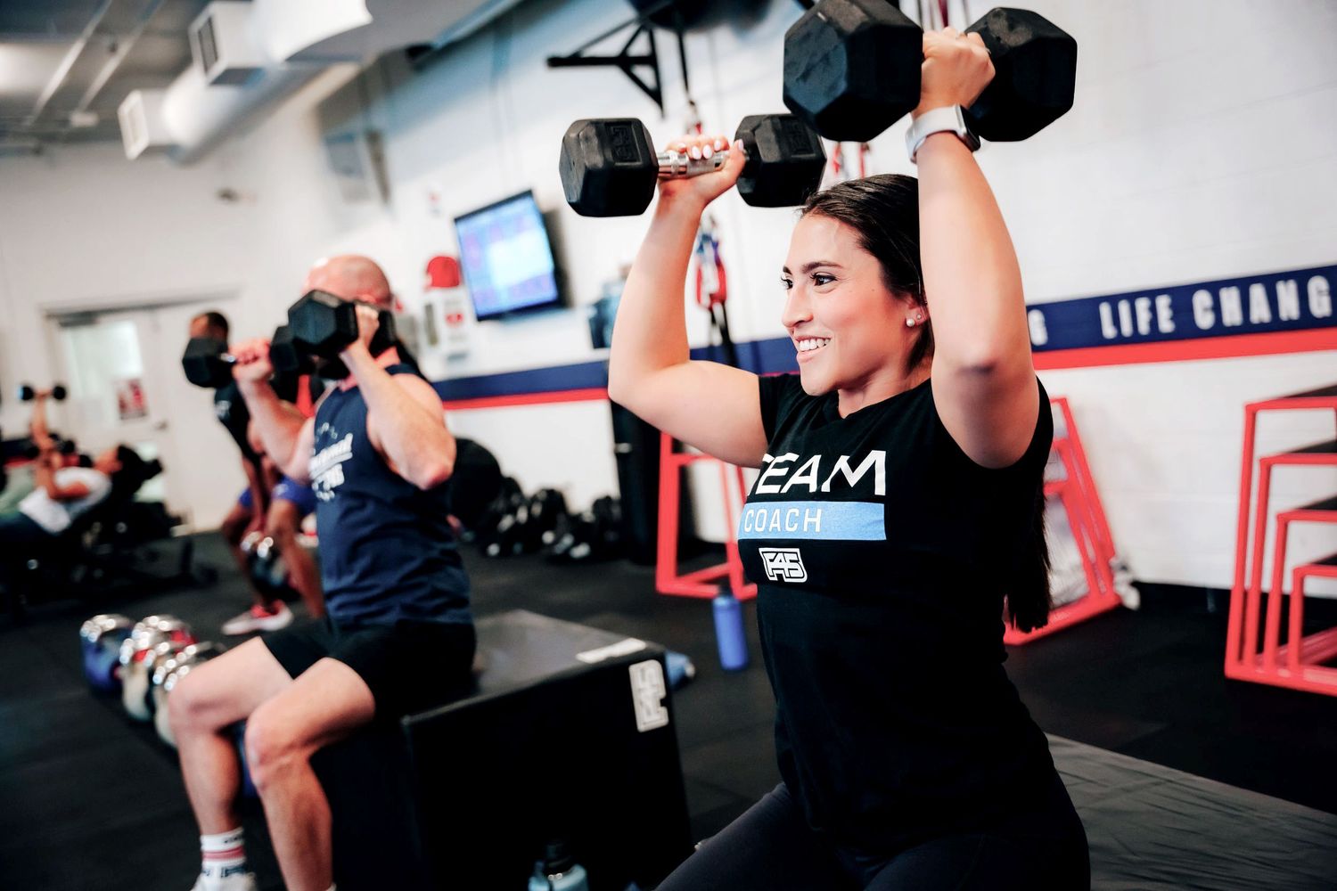 Group fitness class with women lifting weights at a branded gym studio