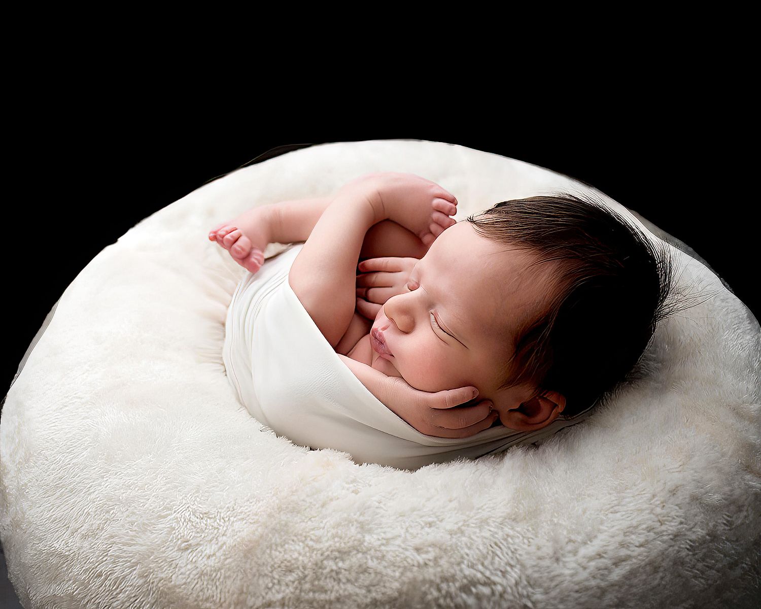 Sleeping newborn baby curled in a white bowl prop against a dark background, fine art newborn photography