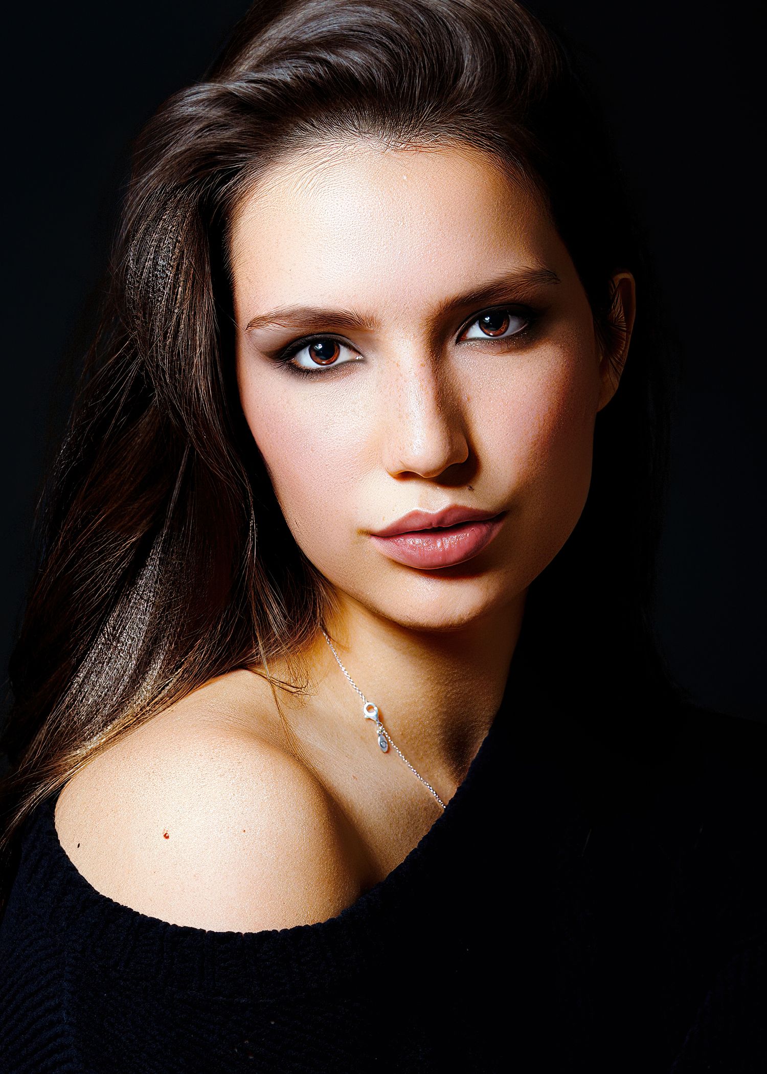 Dramatic studio portrait of a woman with dark hair against a black background