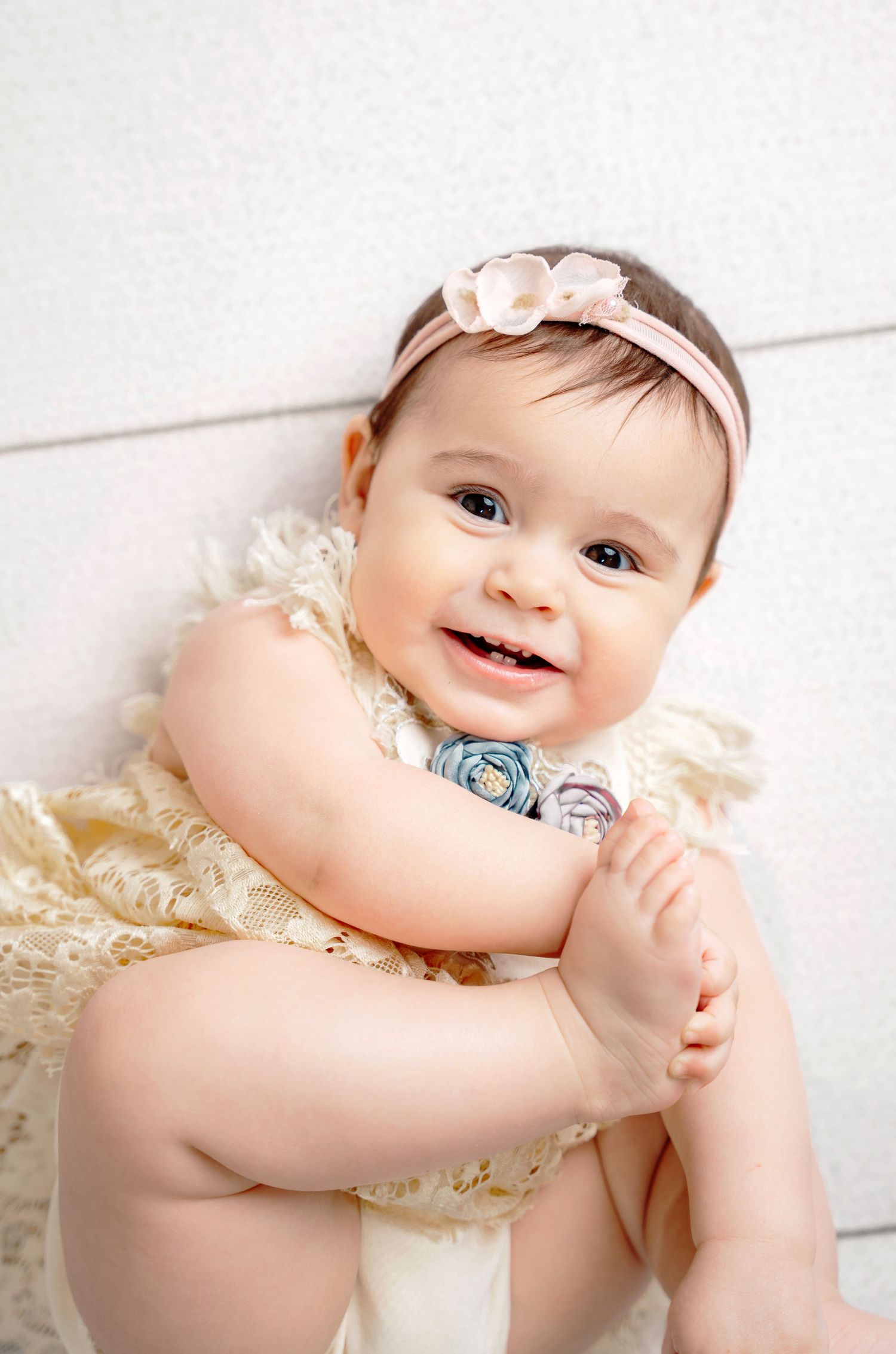 Adorable baby in a studio portrait wearing a headband, soft pink tones