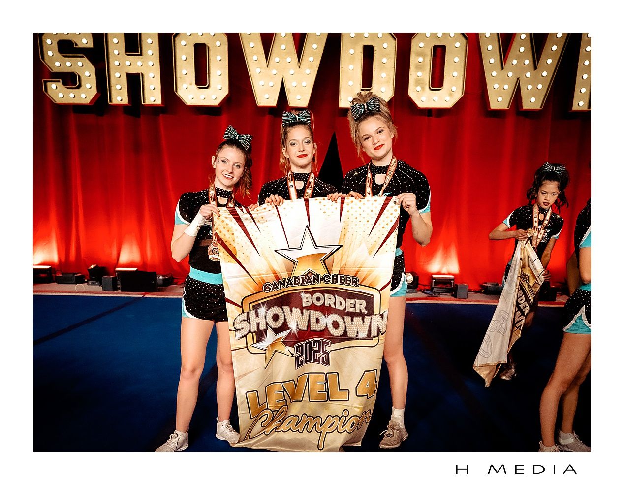 cheerleaders  posing in gold costumes in front of a Showdown banner on stage