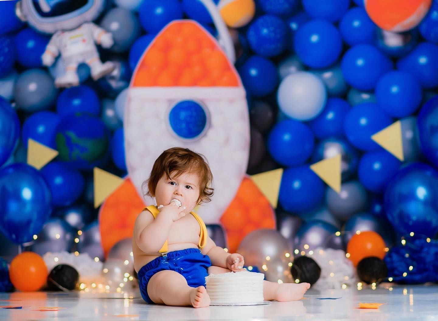 First birthday cake smash portrait with space-themed backdrop and balloon decor