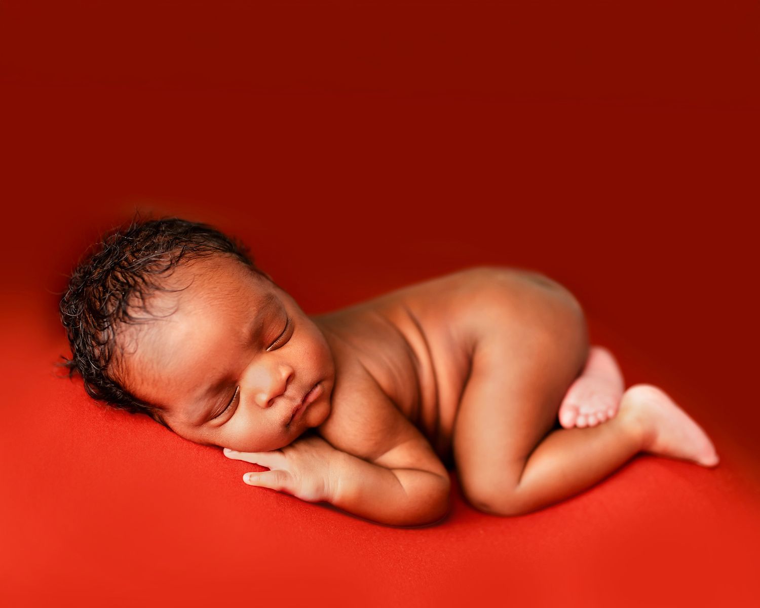 Sleeping newborn baby posed on a red background in a fine art newborn photography studio