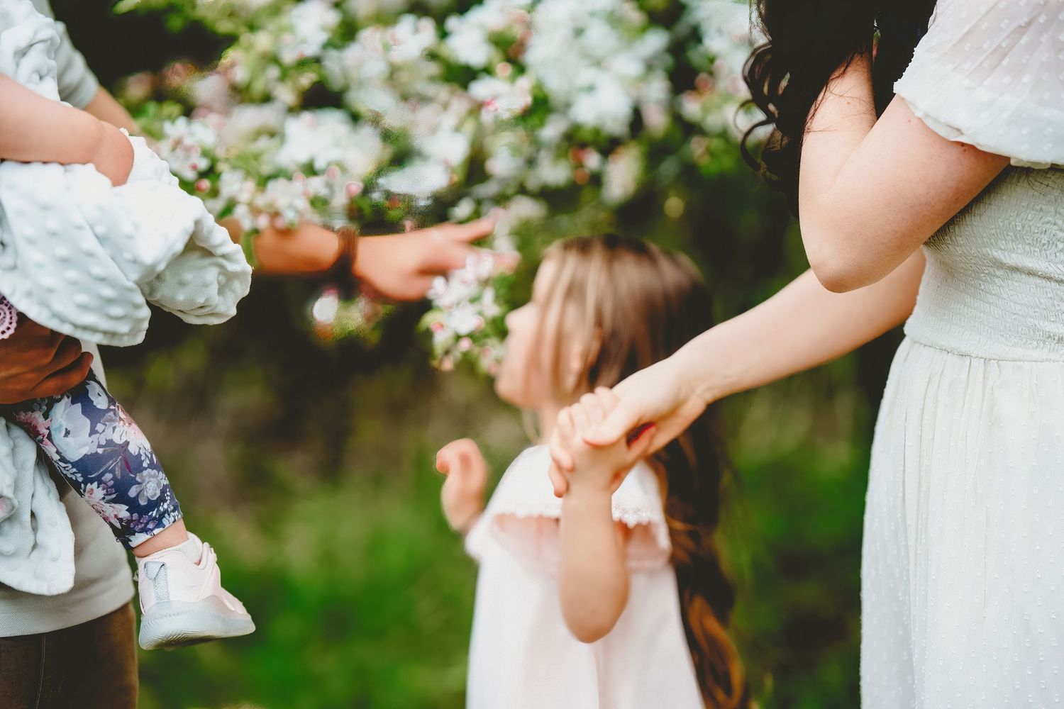 Mother playing with a young child outdoors among blossoming trees in spring