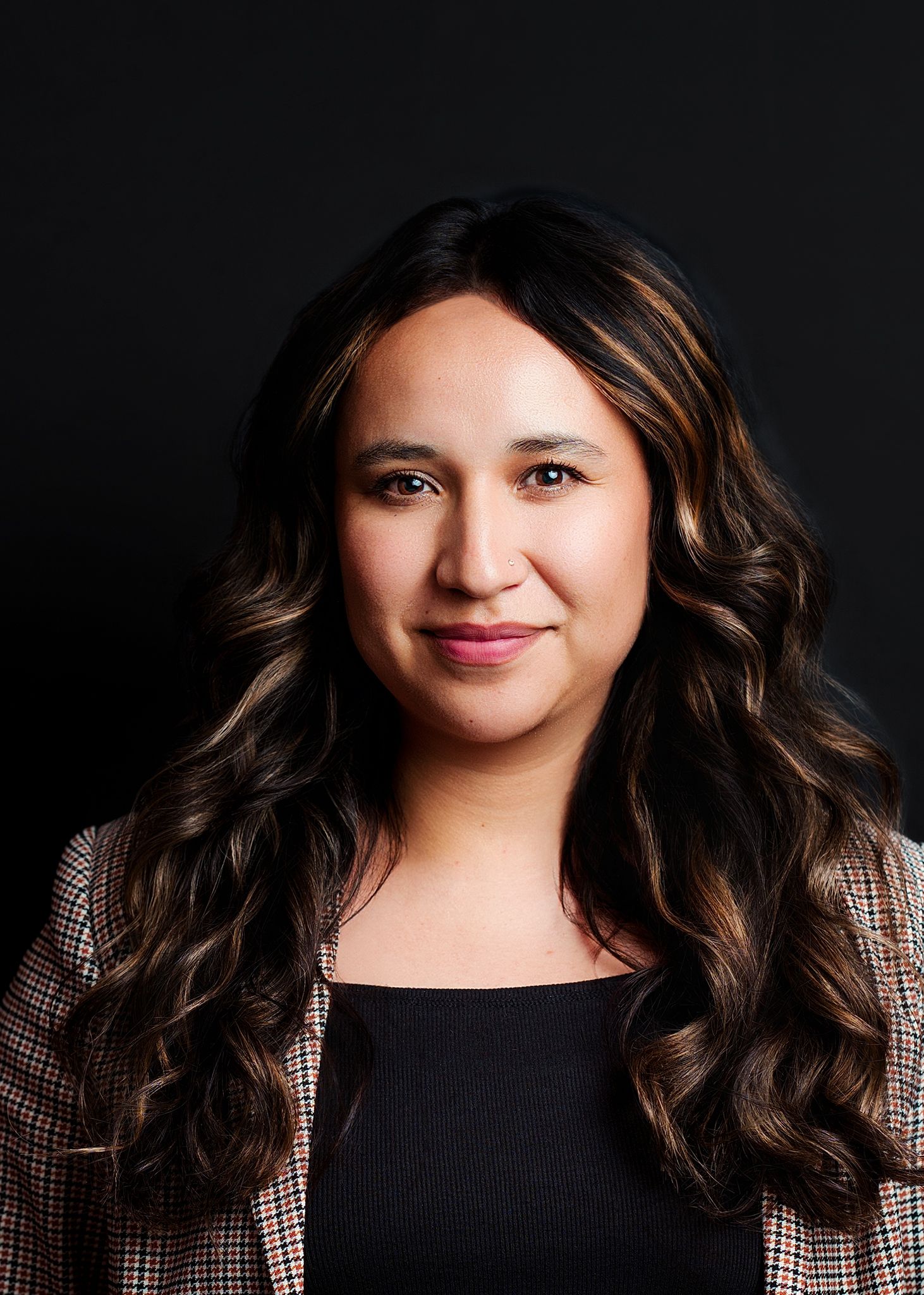Professional headshot of a woman with long dark hair against a dark background