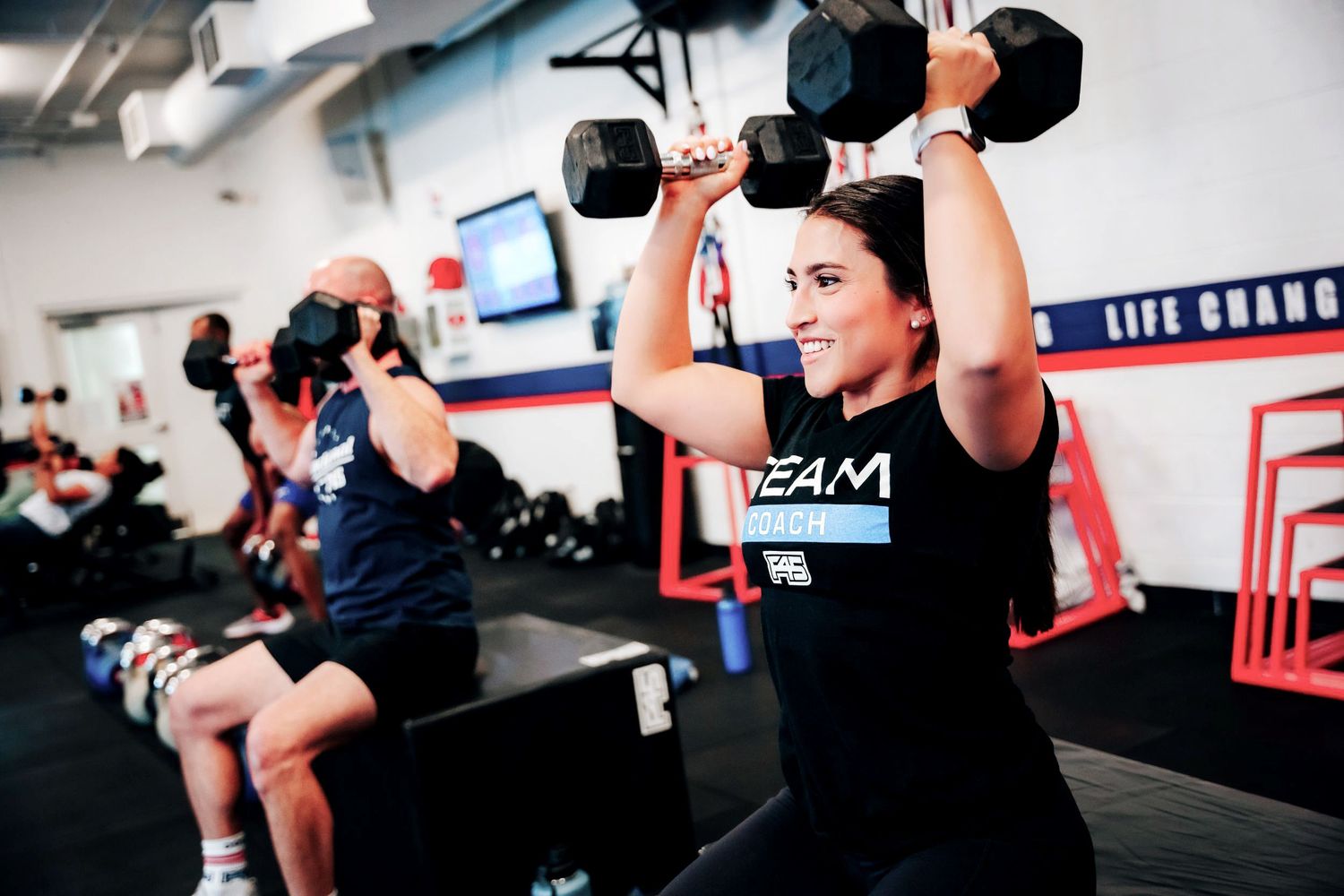 Group fitness class with women lifting weights at a branded gym studio
