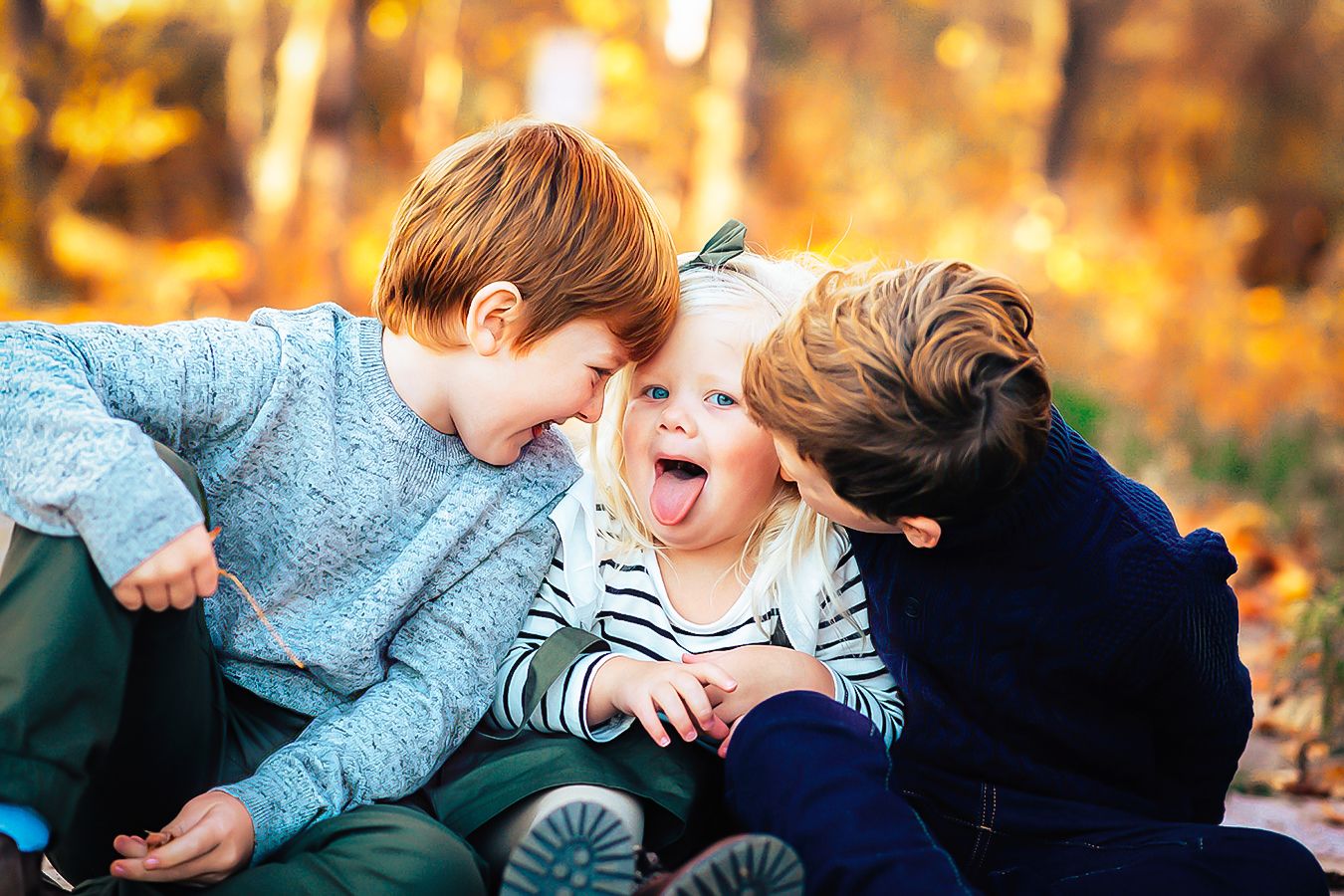 Family with two young children laughing together outdoors in autumn foliage
