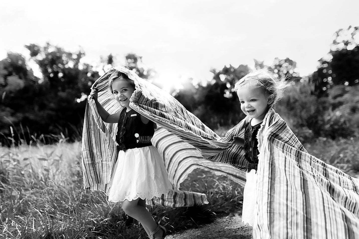 two sisters running outdoors with a blanket