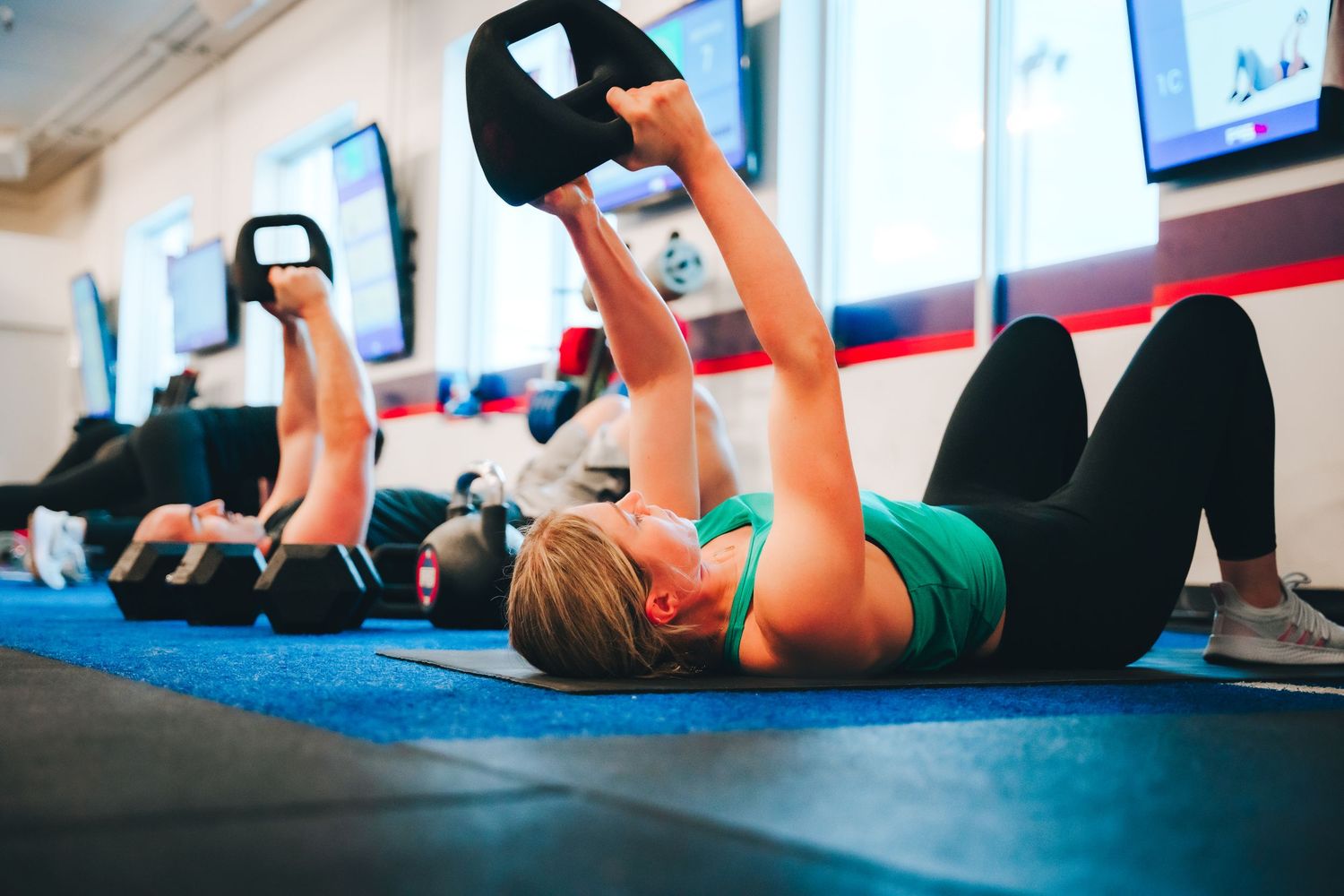 Lifestyle branding photo of group fitness class exercising with weights indoors