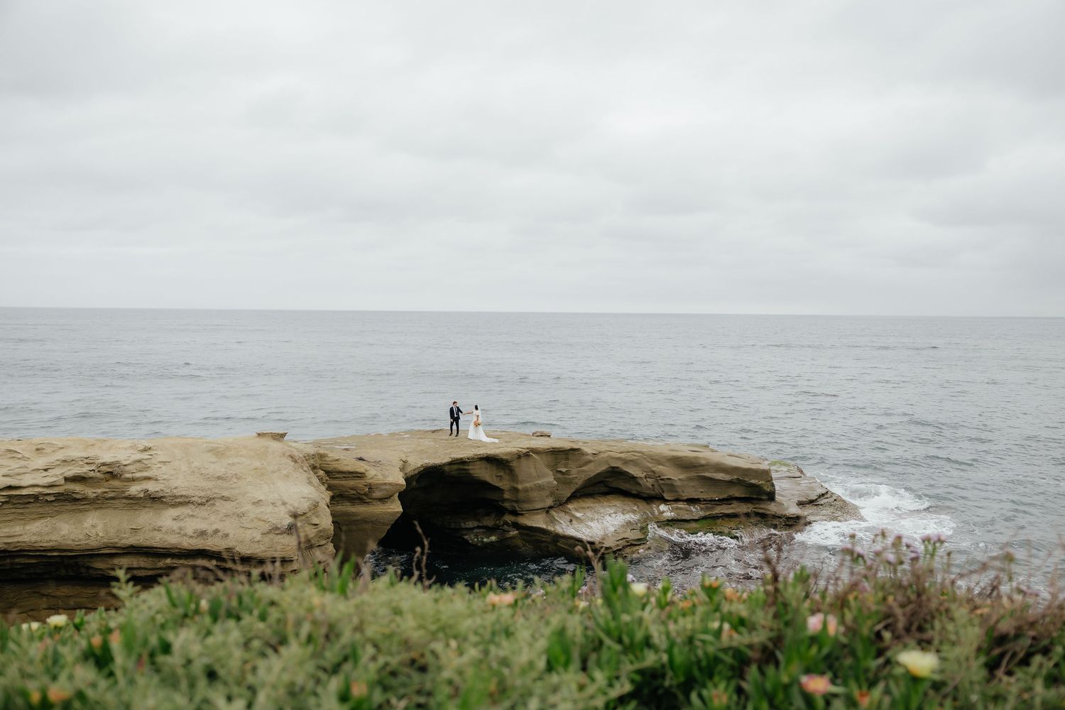 Bride and groom standing on coastal cliffs during a destination wedding
