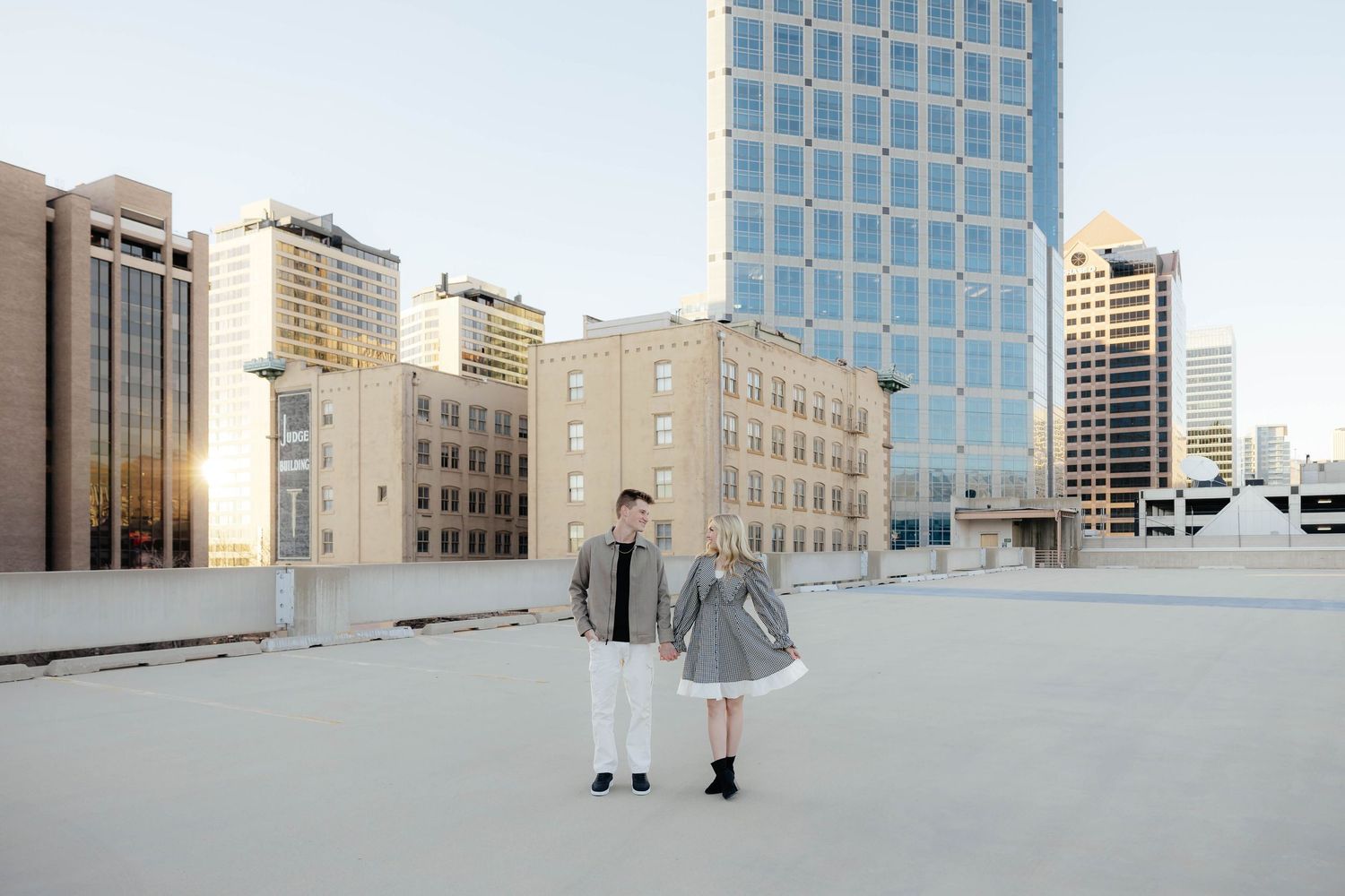 Couple walking together on a rooftop in a modern city setting. Luxury cityscape engagement session.