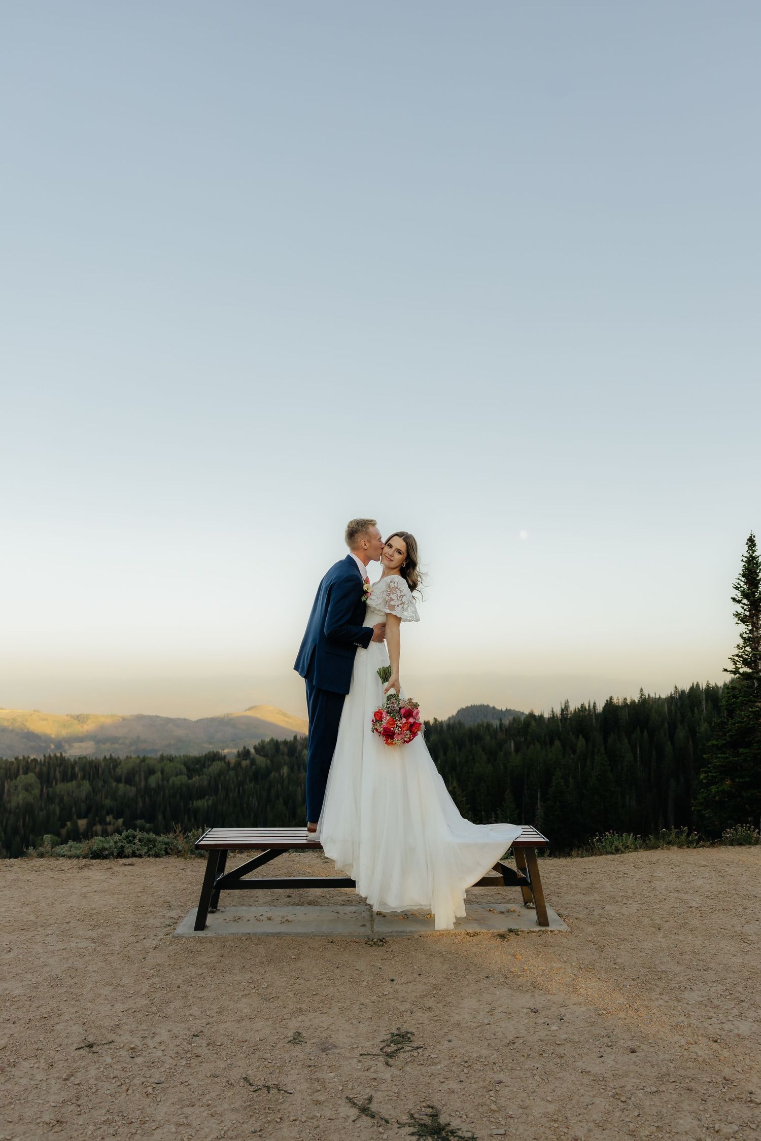 Couple sharing an intimate moment during a bridal session overlooking a valley at sunset.