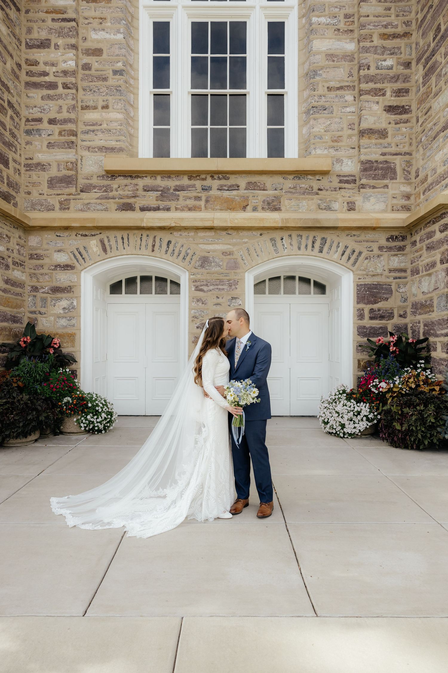 Bride and groom standing outside a stone chapel on their wedding day