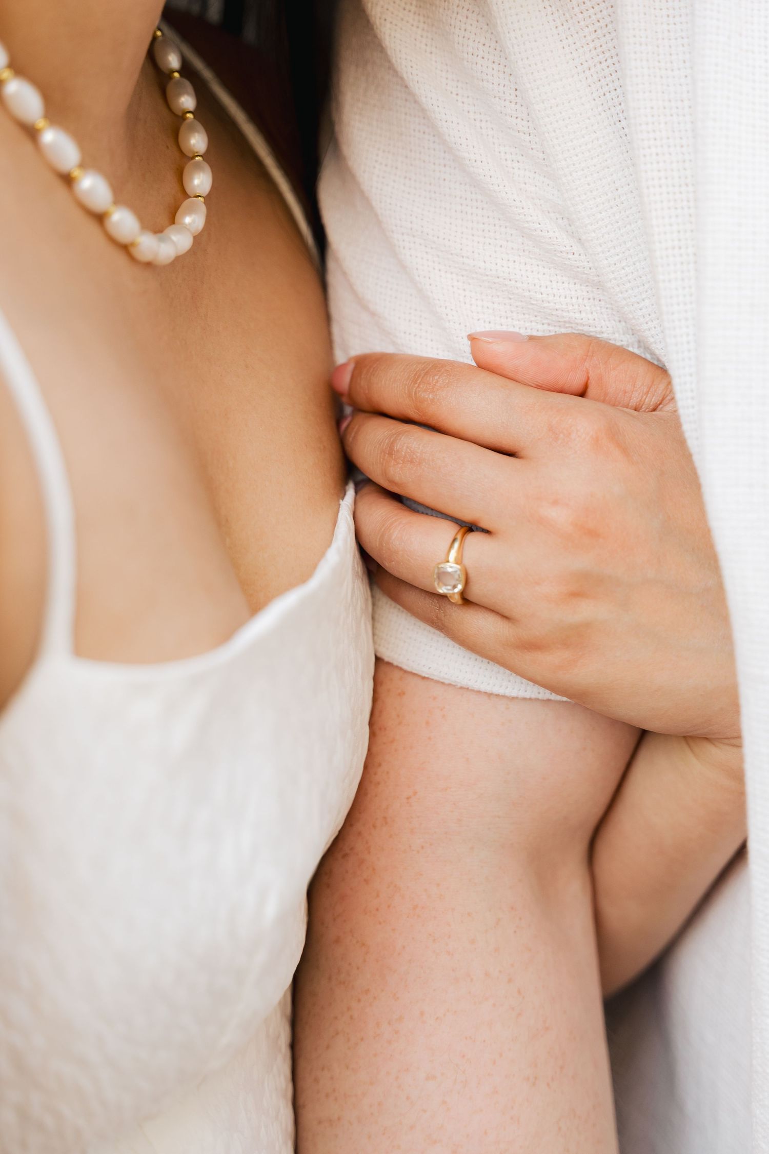 Pearl necklace and wedding ring details shown in close-up shots against white fabric in Halifax, Nova Scotia.
