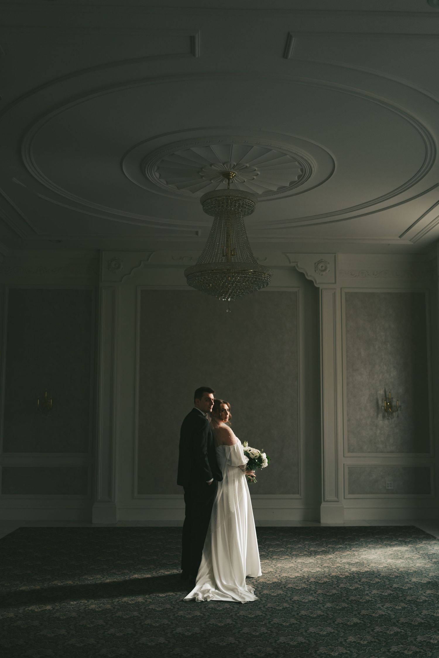 Dramatic wedding portrait in dark room with ornate moldings and single spotlight at Lord Nelson Hotel, Halifax, Nova Scotia.