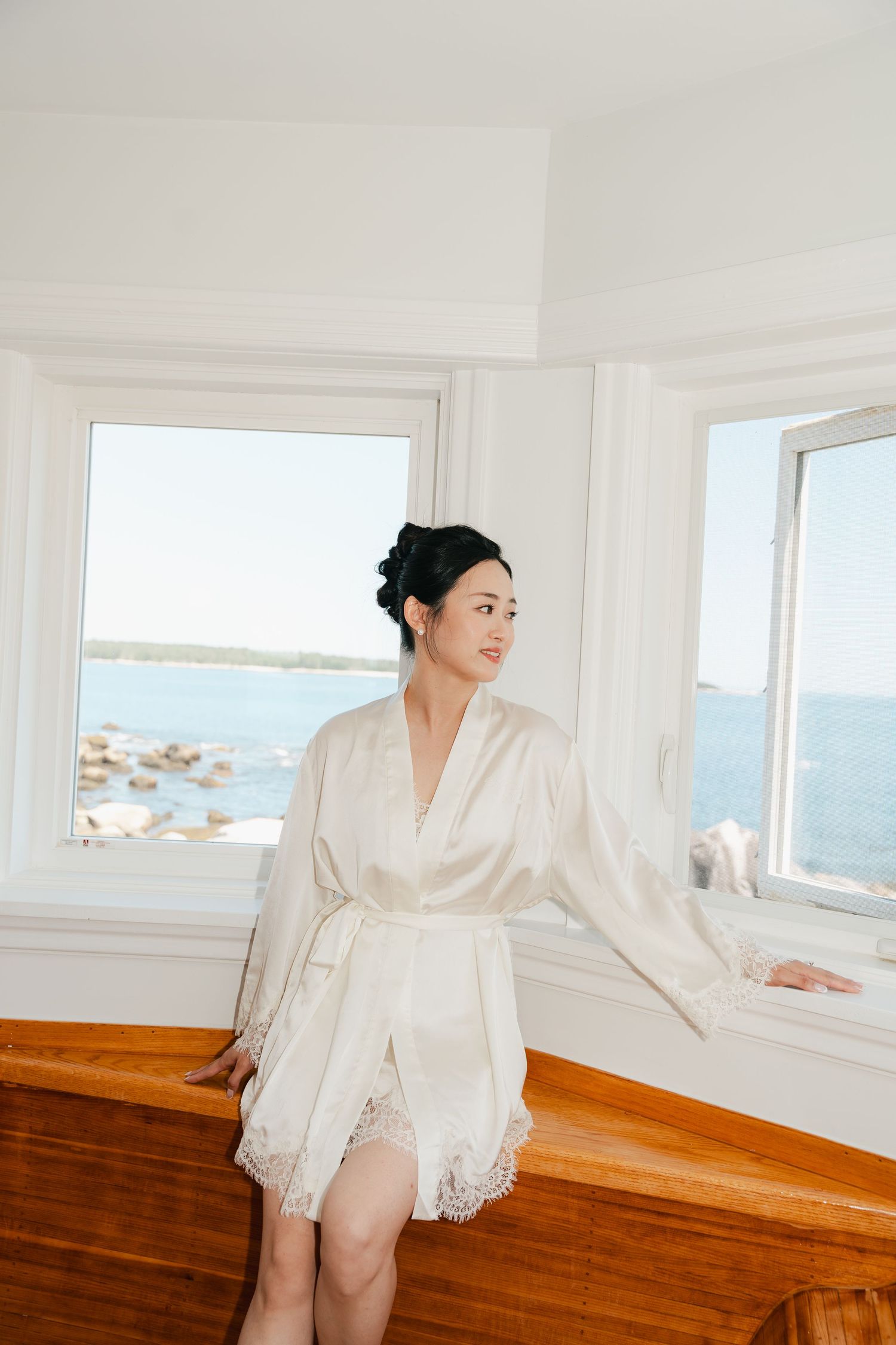 White silk robe against coastal window backdrop in elegant boudoir setting in Halifax, Nova Scotia.
