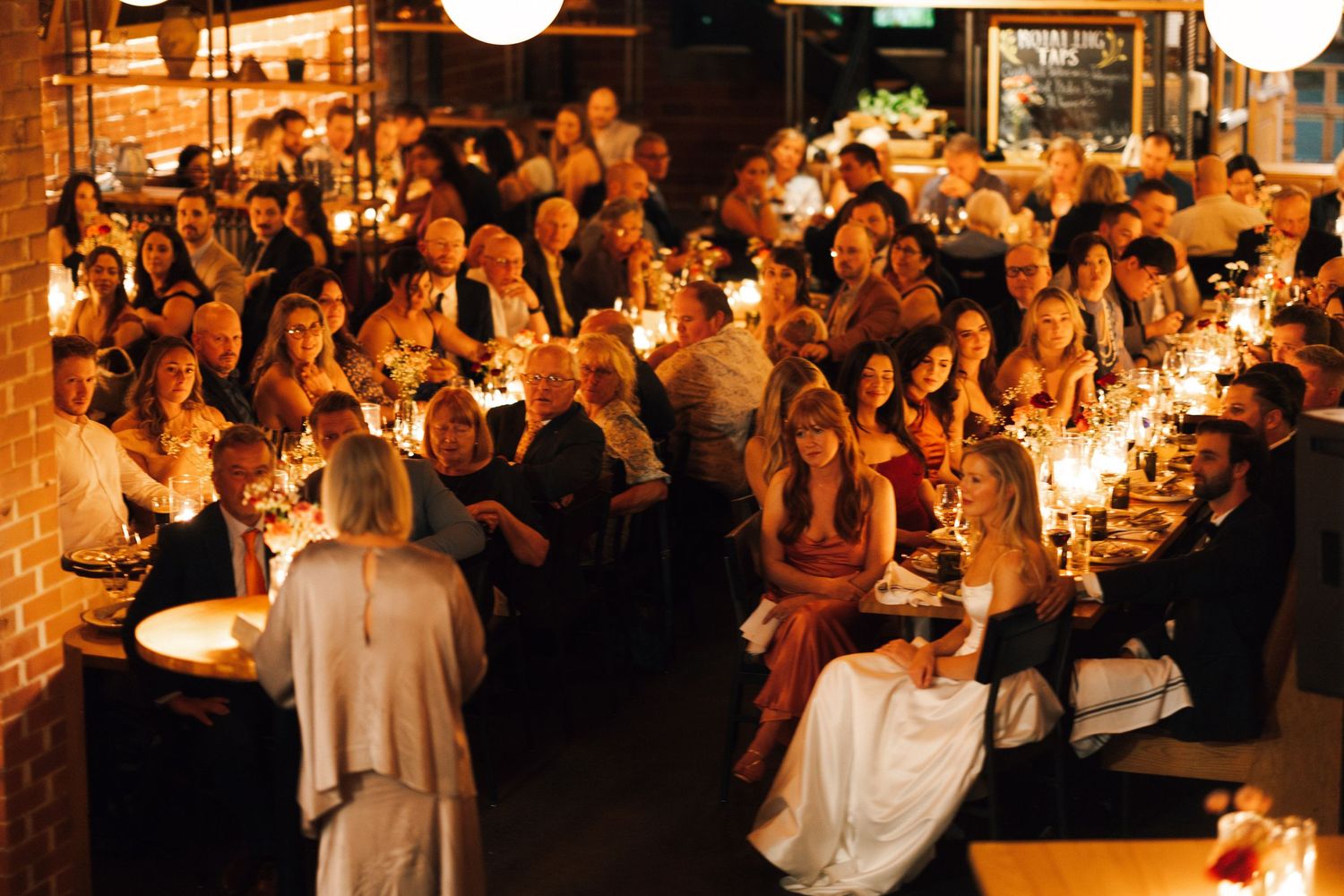 A warmly lit reception hall filled with guests celebrating at tables with glowing candlelight in Halifax, Nova Scotia.
