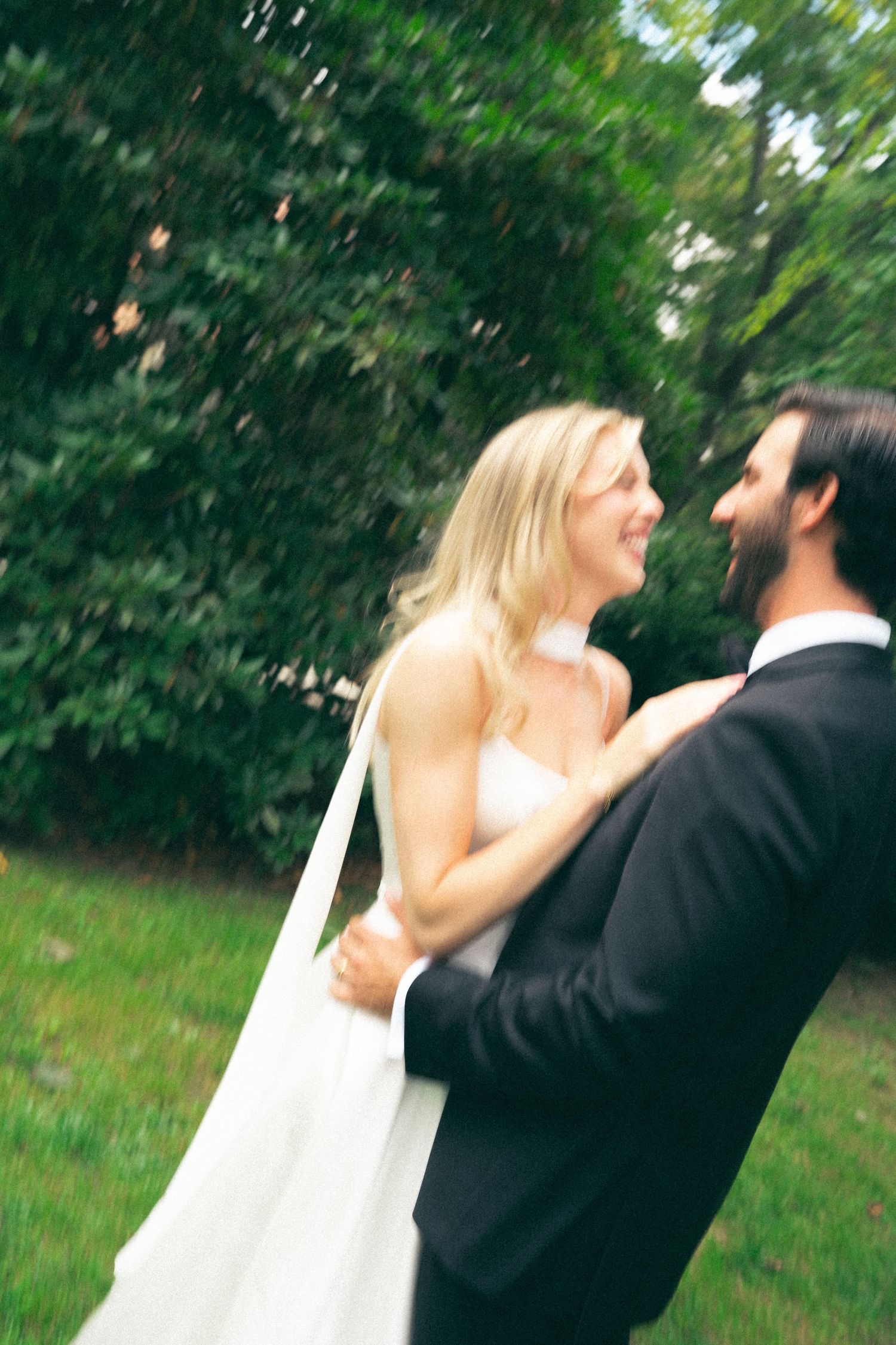 A joyful couple dancing and twirling outdoors surrounded by greenery in Halifax, Nova Scotia.