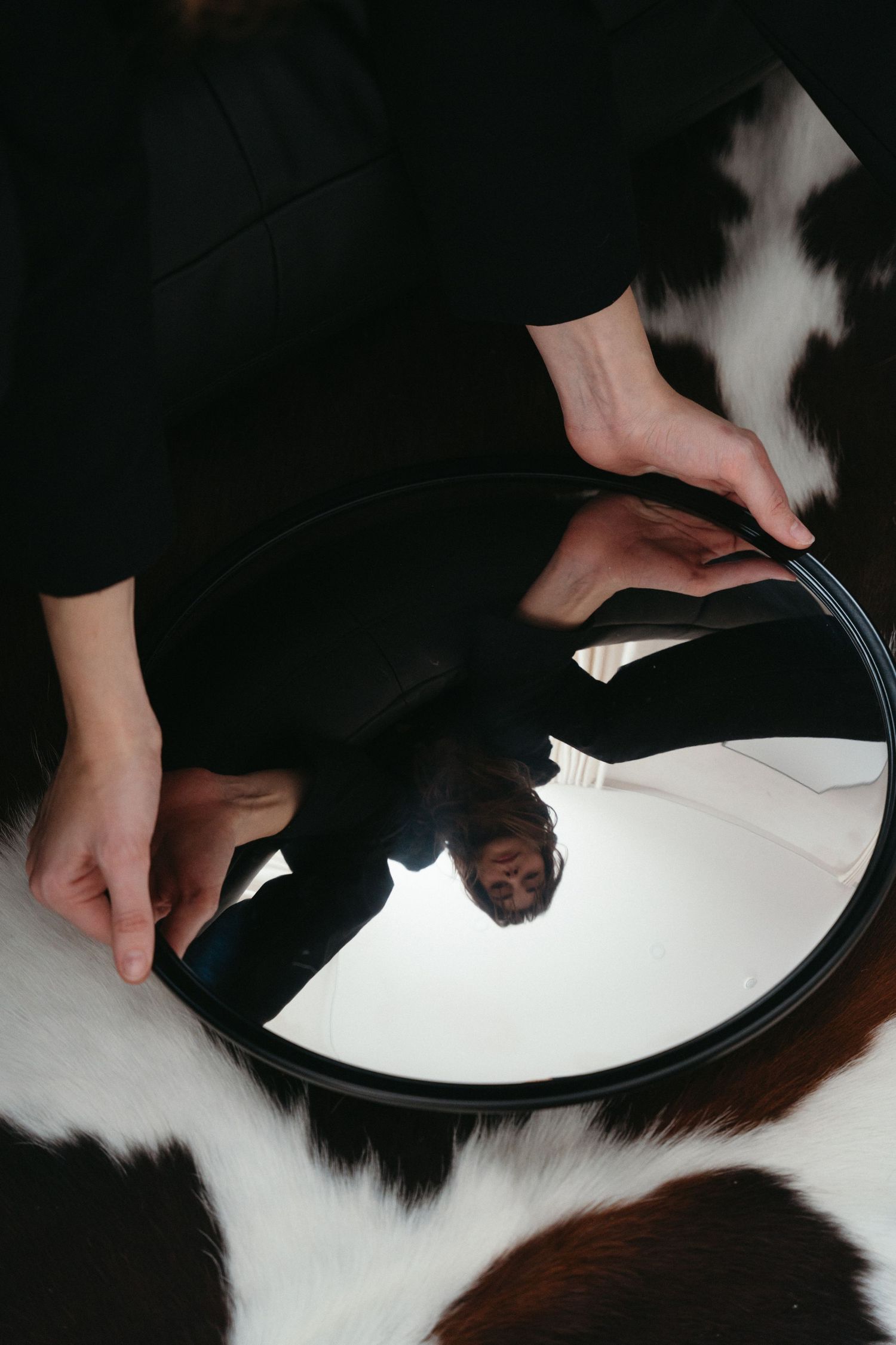 Hands arranging circular black and white objects in artistic composition in Halifax, Nova Scotia.