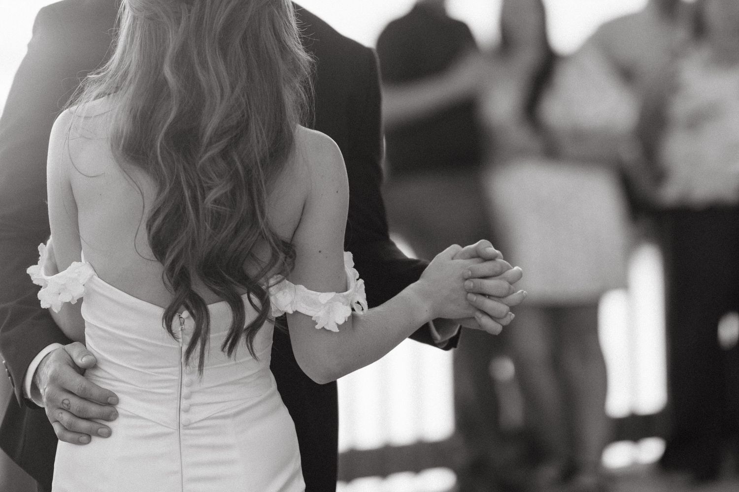 A couple shares their first dance at a wedding reception while guests look on from the background in Halifax, Nova Scotia.