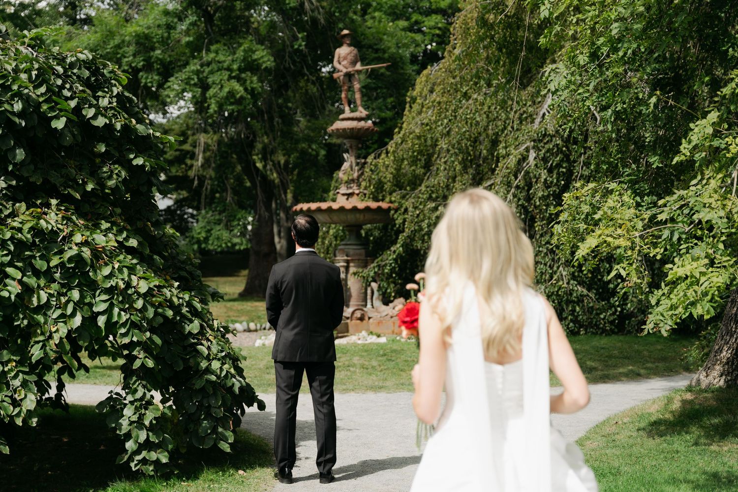 A couple shares an intimate moment in a lush garden setting during their wedding photoshoot in Halifax, Nova Scotia.