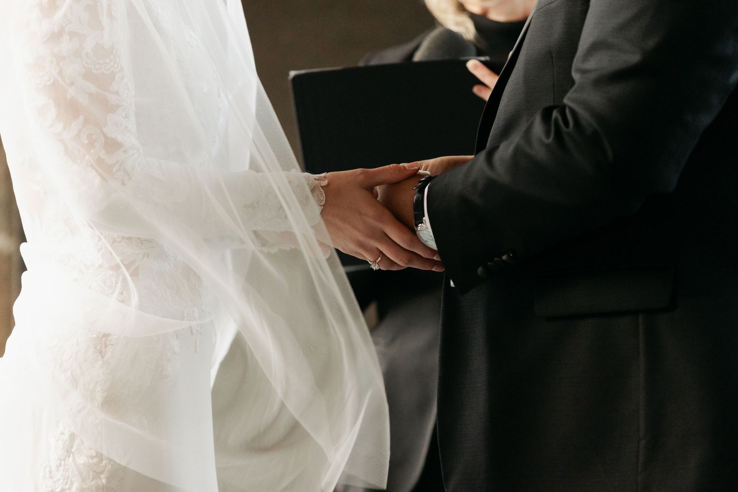 Wedding ceremony participants share intimate moments in formal attire against a light background at Lightfoot & Wolfville.