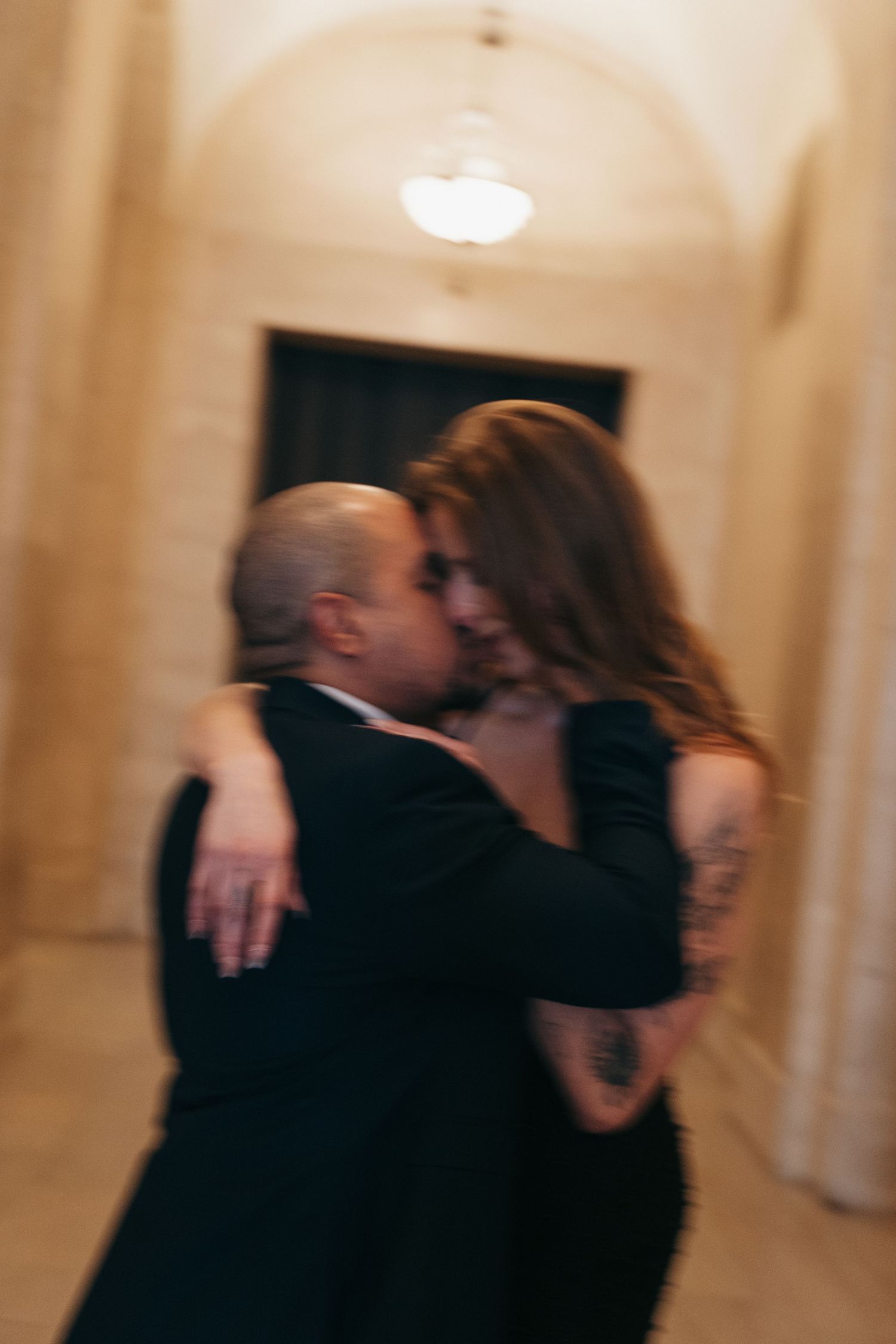 A romantic cinematic photo showing a couple embracing in a dimly lit hallway in Montreal, Quebec.
