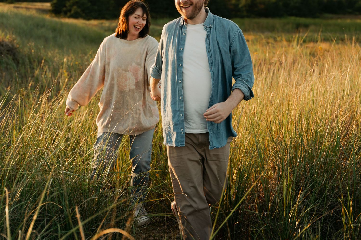 Couple walking through tall grass field during golden hour photo session in Halifax, Nova Scotia.