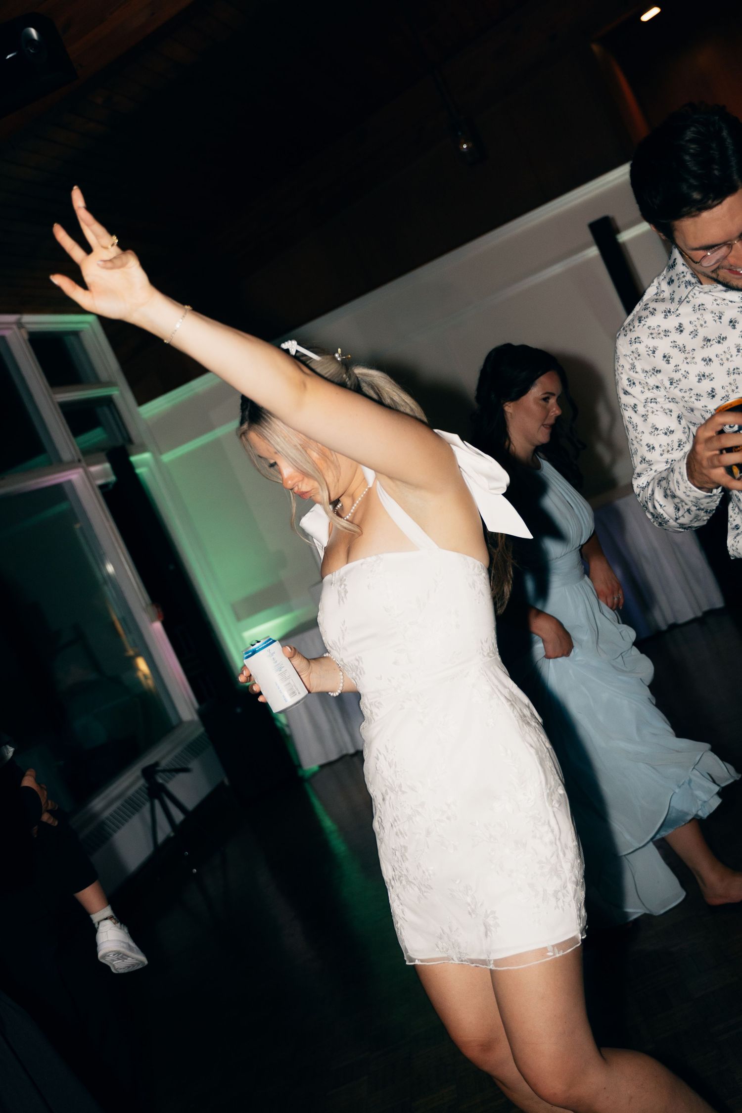 Wedding party dancing enthusiastically in a dark reception venue with ambient lighting in Halifax, Nova Scotia.