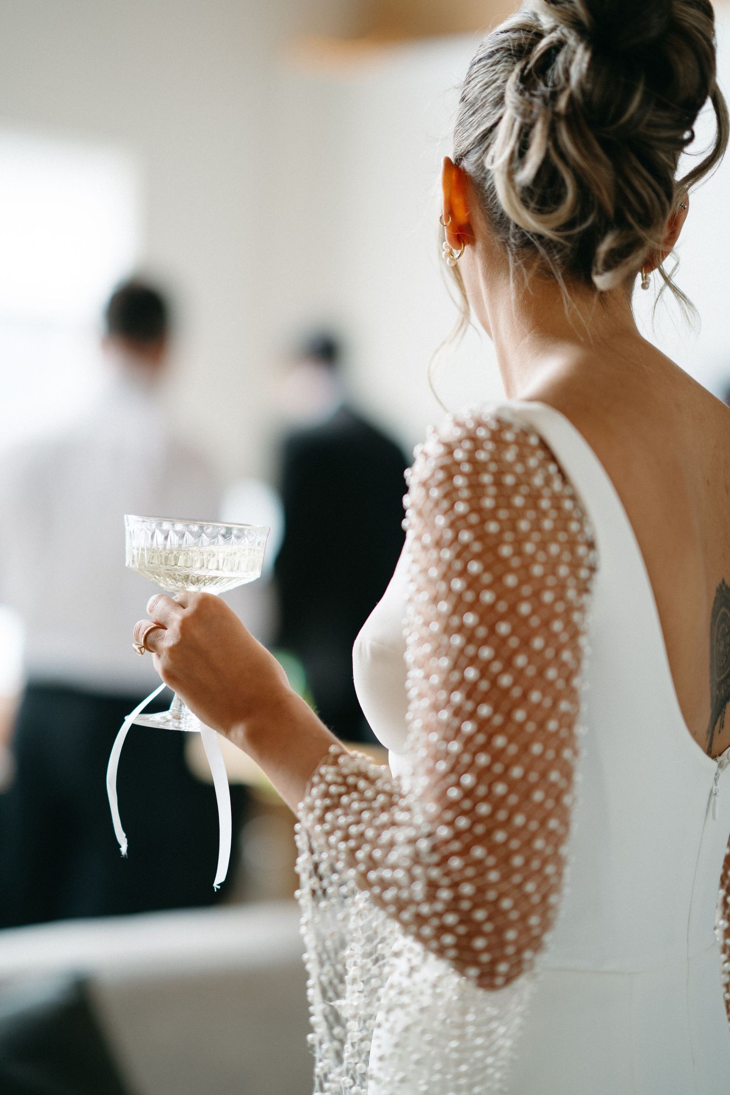 Close-up details of a white wedding dress with delicate pearl embellishments and sheer sleeves in a bridal getting ready scene in Halifax.