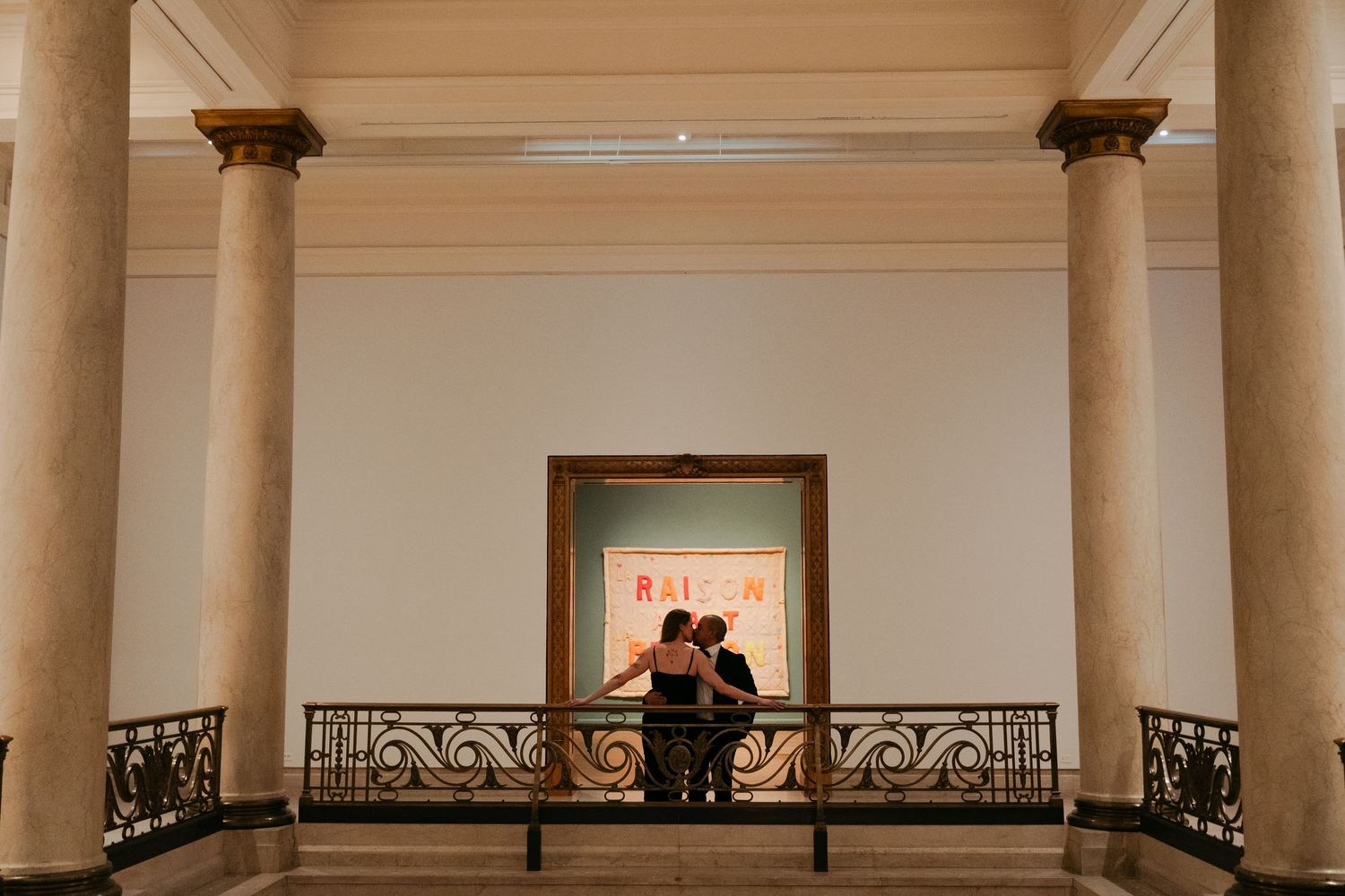 A grand interior space with classical columns and ornate railings features a couple dancing in silhouette at the far end in Montreal, Quebec
