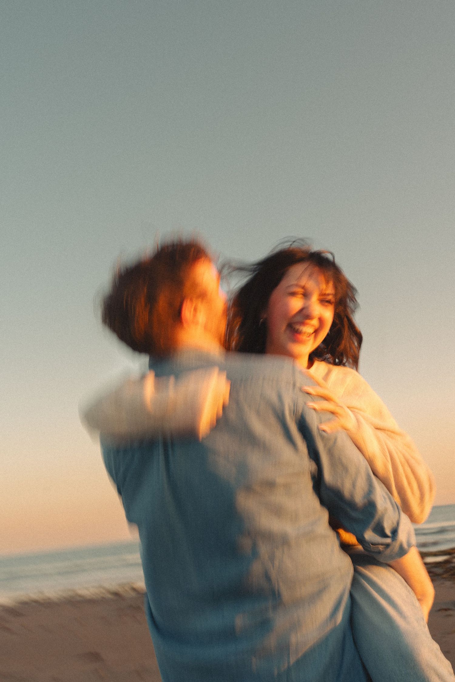 A sequence of cinematic motion blur photos showing a person spinning joyfully at sunset on a beach in Halifax, Nova Scotia.