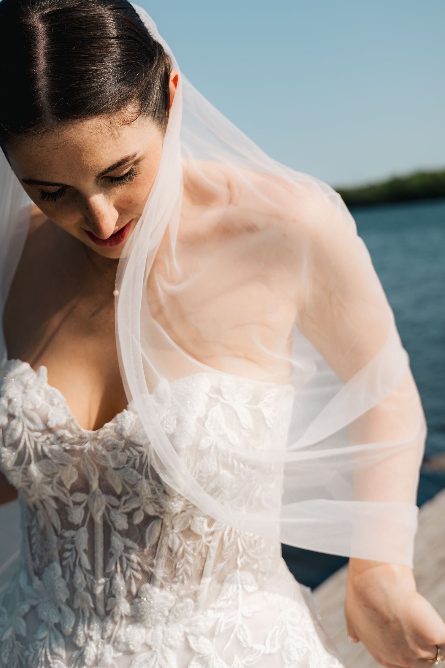 Close-up details of a bride's white wedding dress with delicate lace and tulle veil against a waterfront backdrop in Halifax, Nova Scotia.