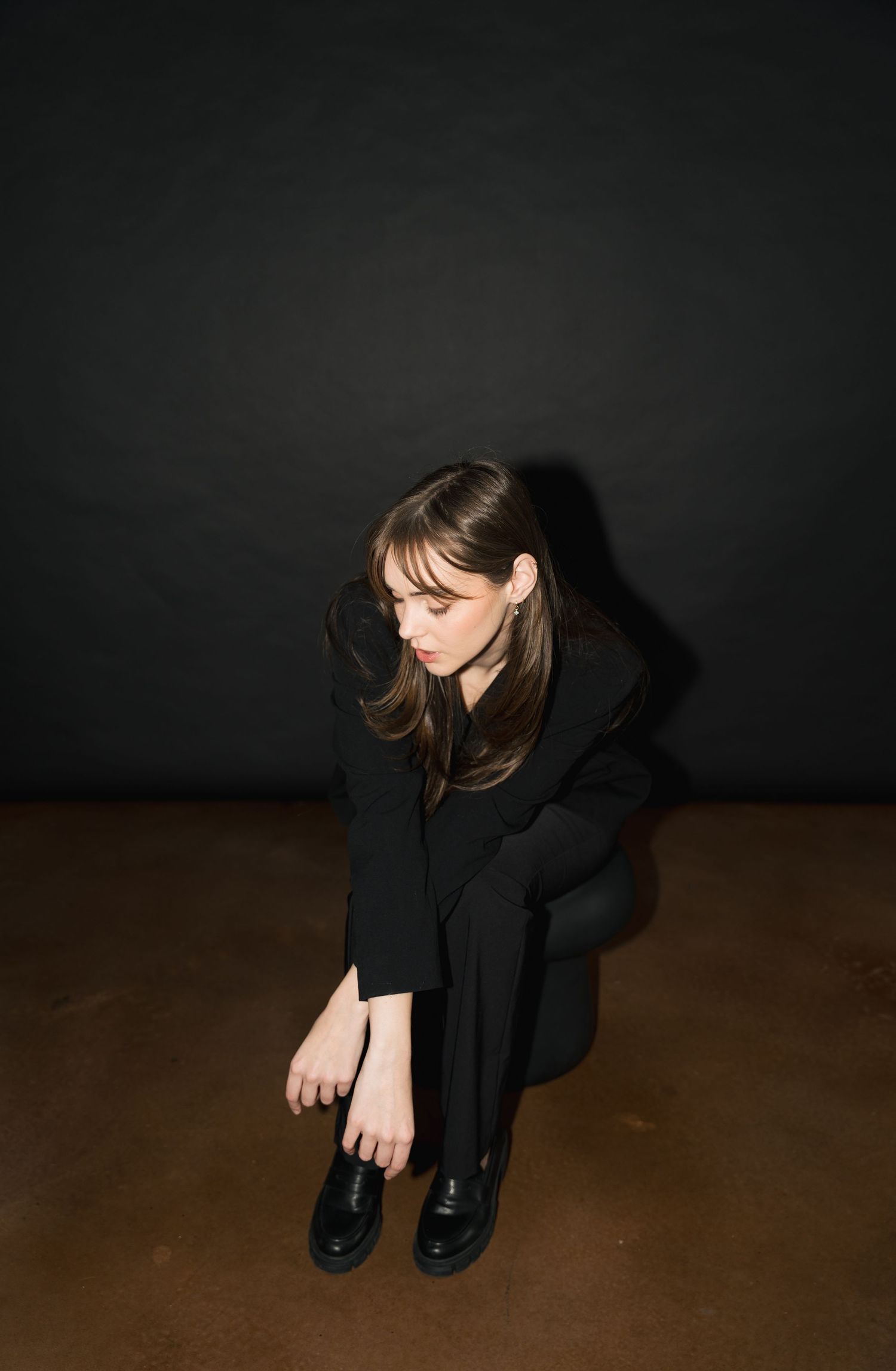 Moody artistic portrait series showing figure in black outfit crouched in dark setting in Halifax, Nova Scotia.