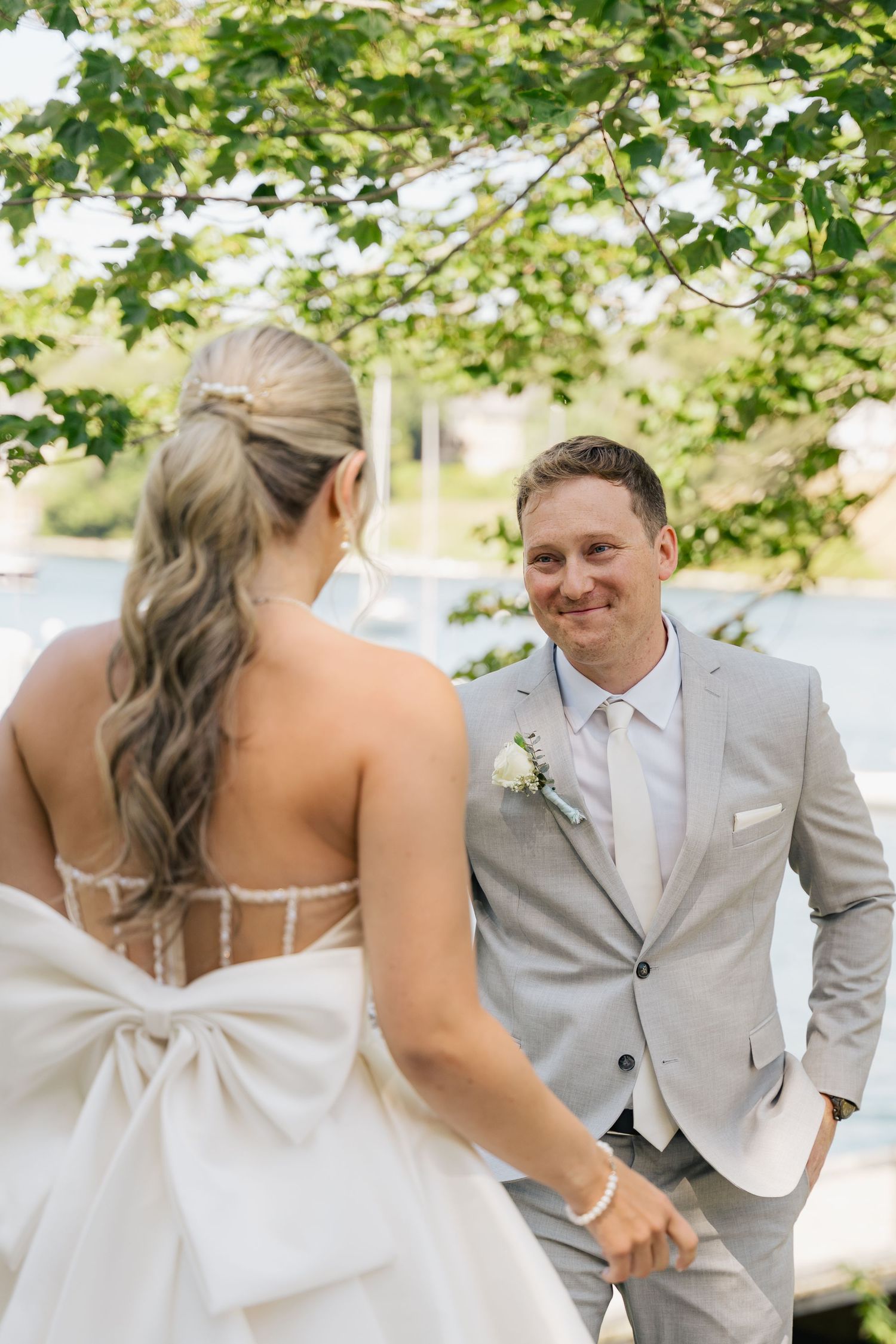 A couple shares a sweet moment under green trees during their outdoor wedding photoshoot in Halifax, Nova Scotia.