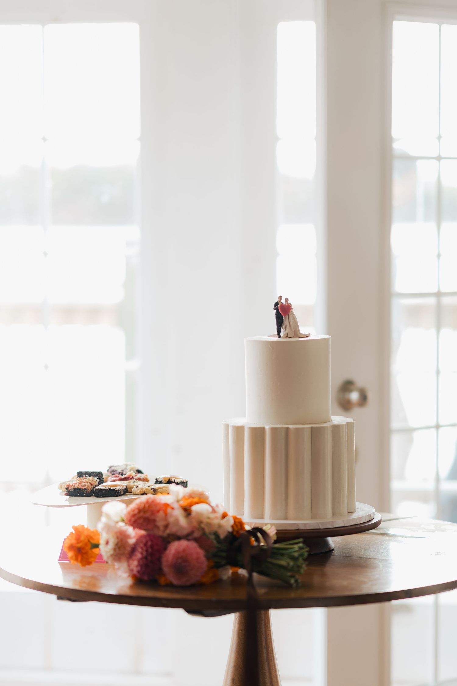 Elegant wedding cakes displayed on wooden stands with orange and pink floral decorations in Nova Scotia.