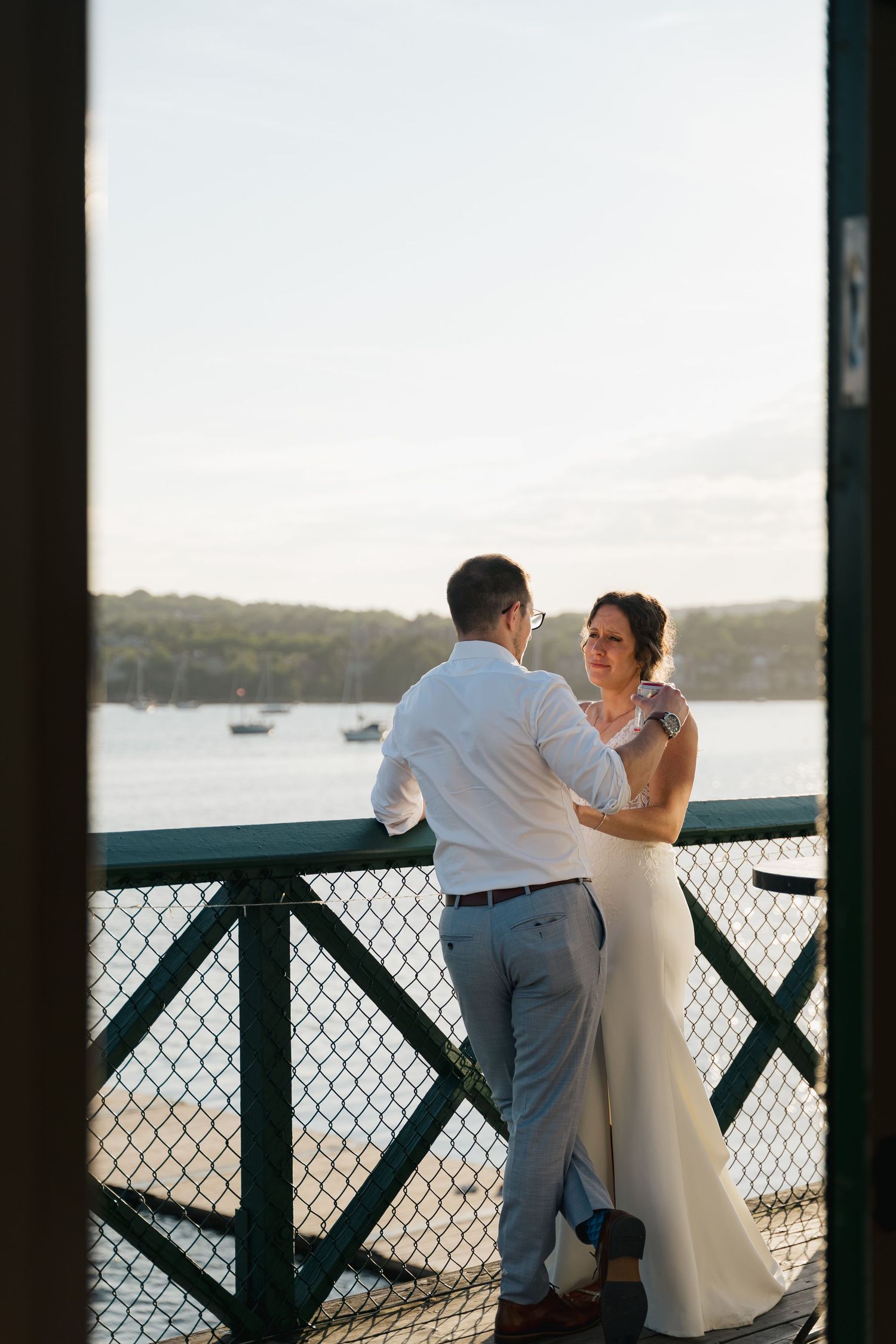 A couple shares a romantic moment on a waterfront deck with boats and water views in the background in Halifax, Nova Scotia.