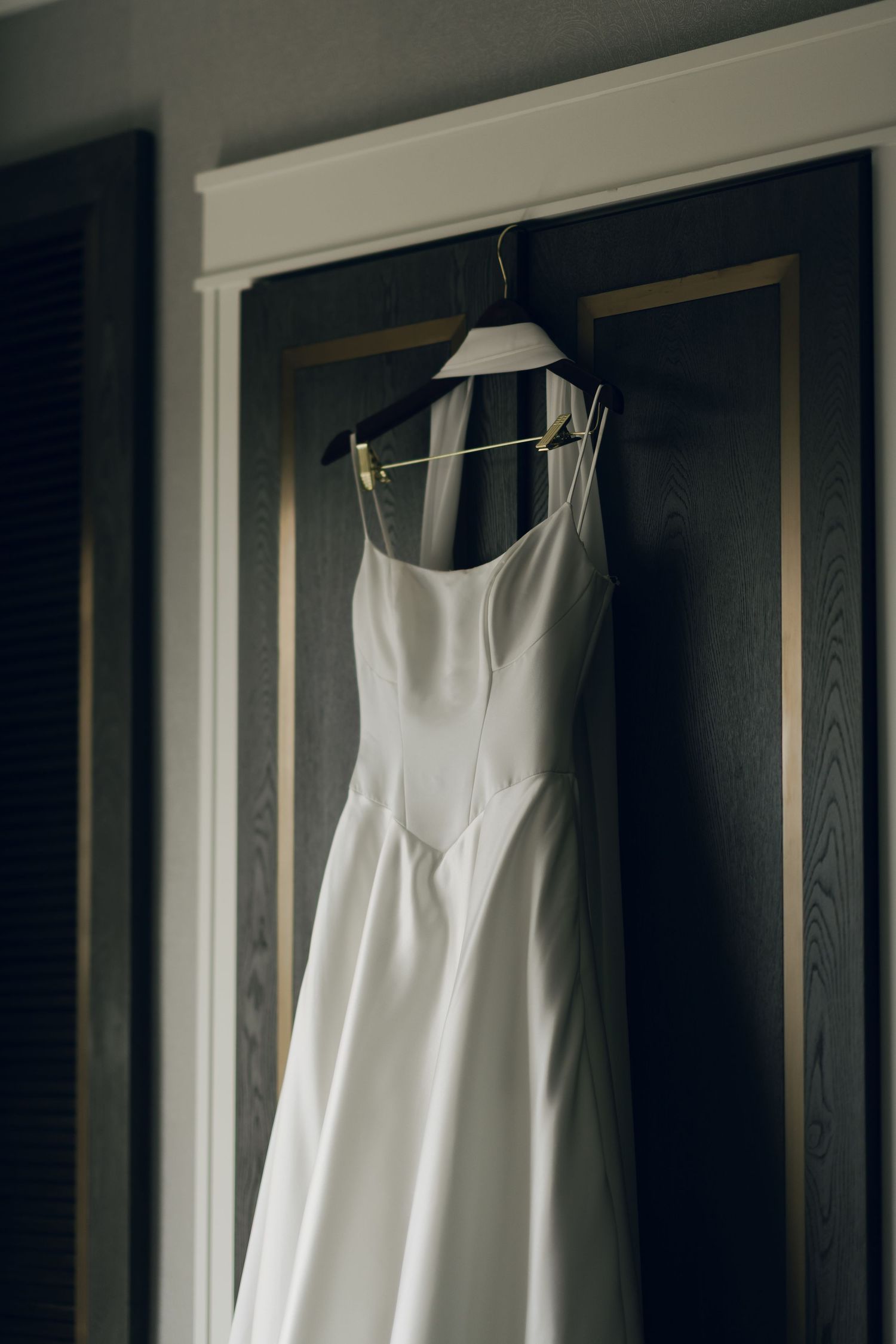 White wedding dress hanging in sequence showing different angles in dark wooden closet in Halifax, Nova Scotia.