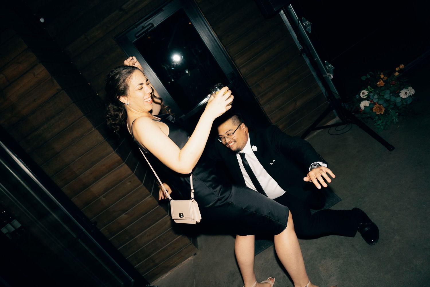 Energetic dance moves captured at a wedding reception in a dimly lit Lightfoot & Wolfville as a venue.