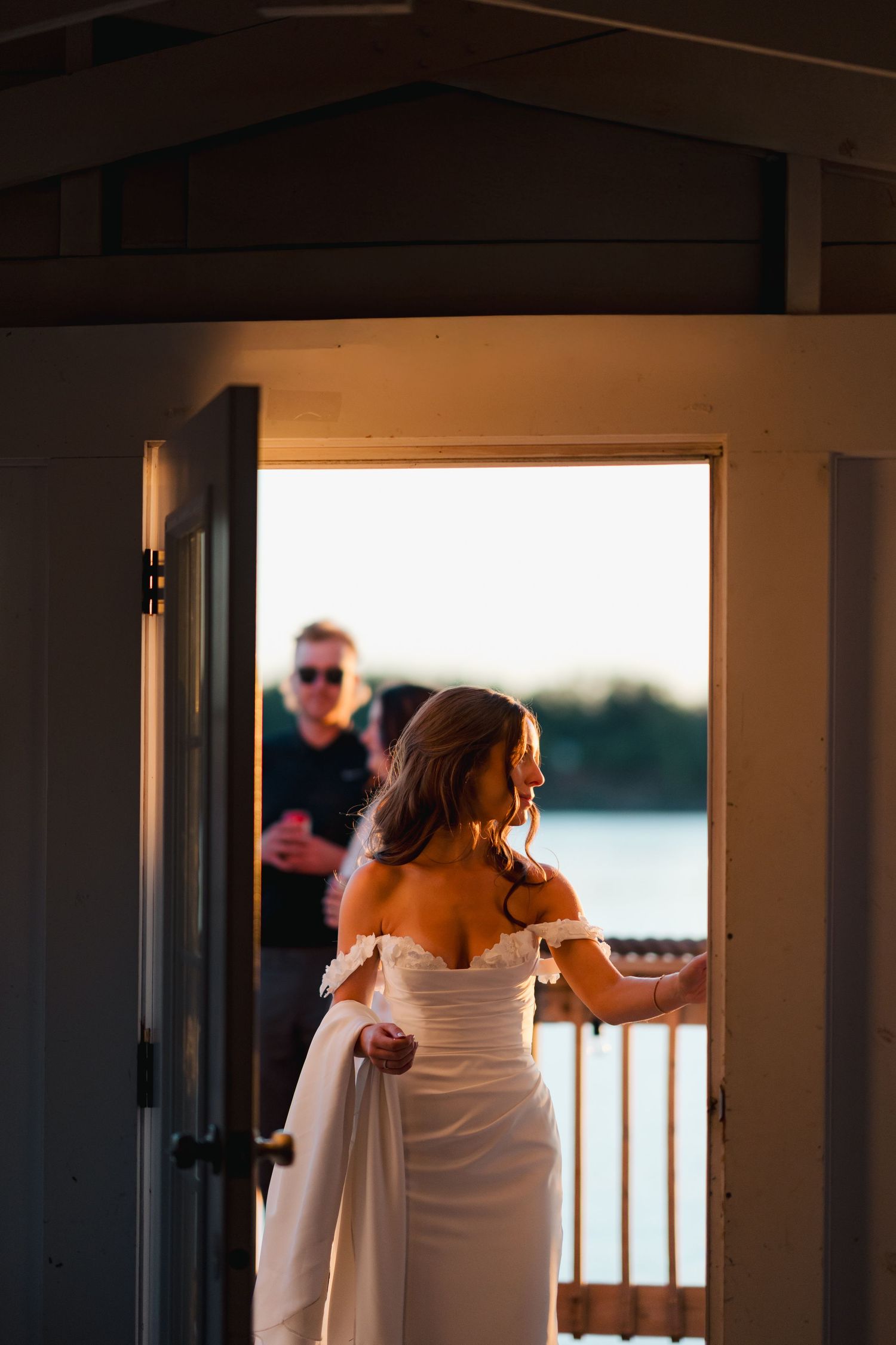 Silhouetted figures against window light during sunset at waterfront wedding venue in Halifax, Nova Scotia.