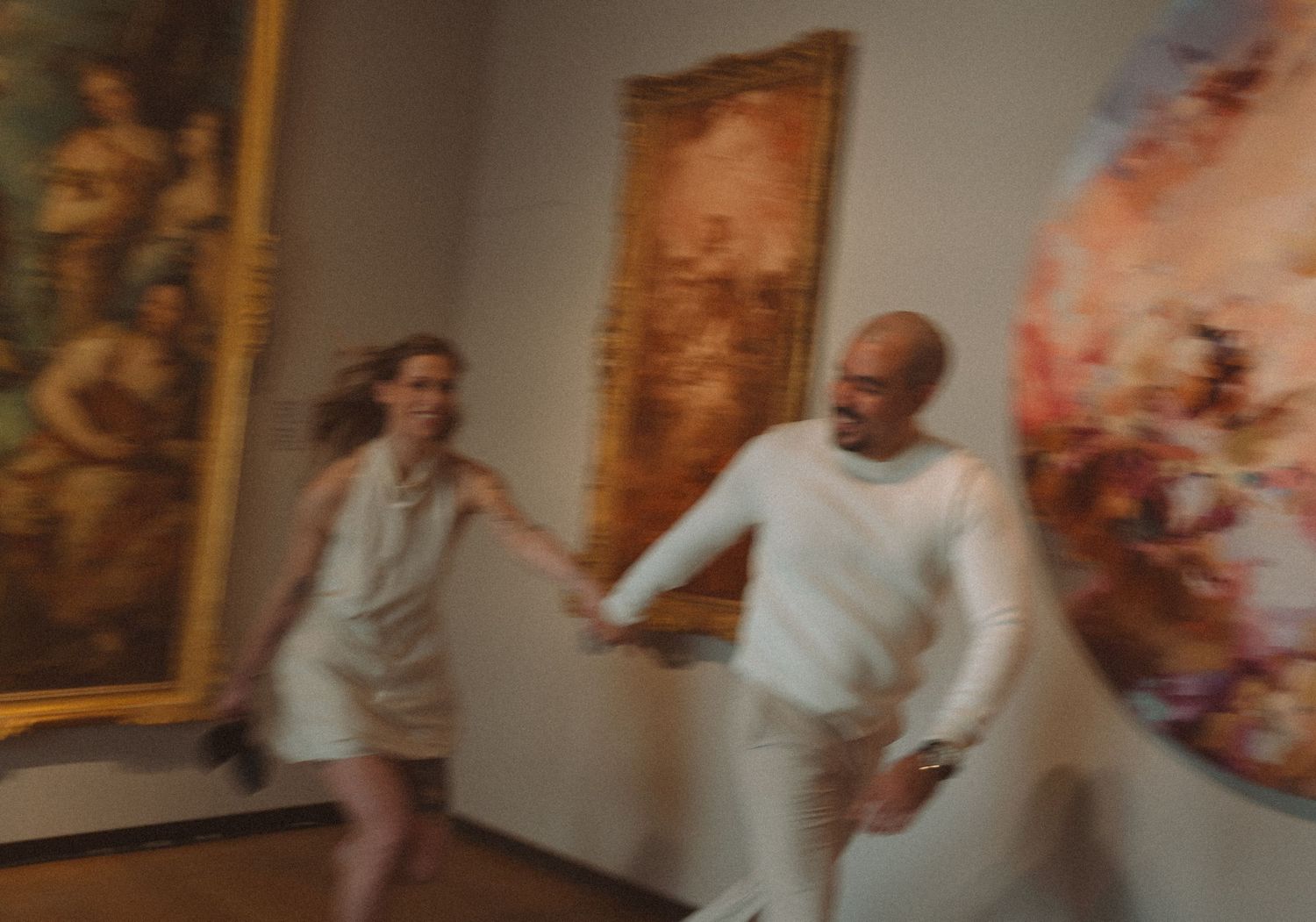 A couple dances in a dimly lit room with ornate paintings on the wall in Montreal, Quebec.