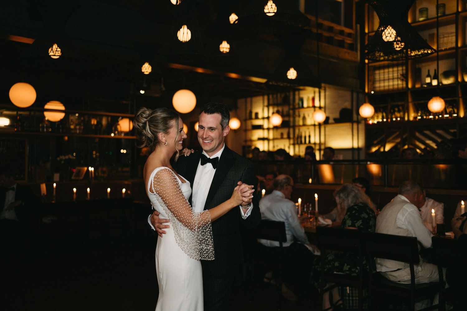 Wedding reception venue decorated with hanging lanterns and warm lighting as guests dance and celebrate  in Halifax, Nova Scotia.