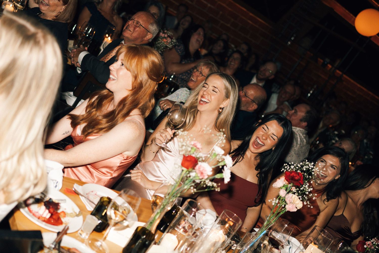 Wedding reception guests celebrating at tables with warm ambient lighting in Halifax, Nova Scotia.